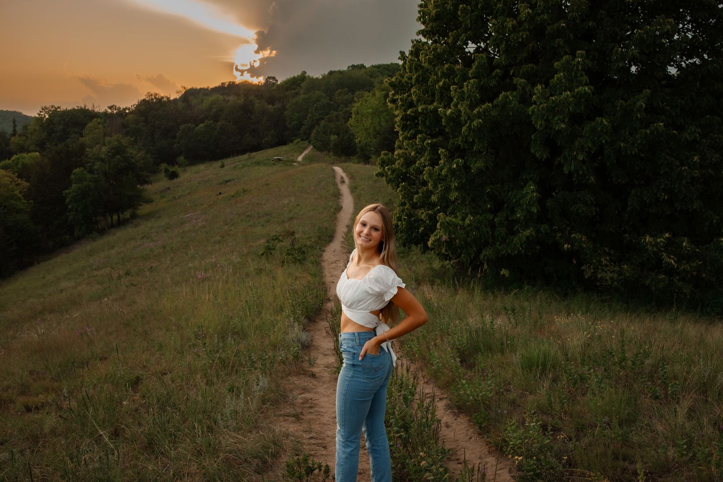 A casual summer portrait on a hilltop trail during golden hour sunset.