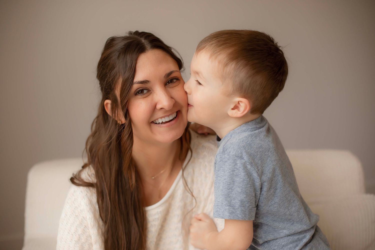 A heartwarming moment between a mother and young child sharing laughter while sitting on a couch.