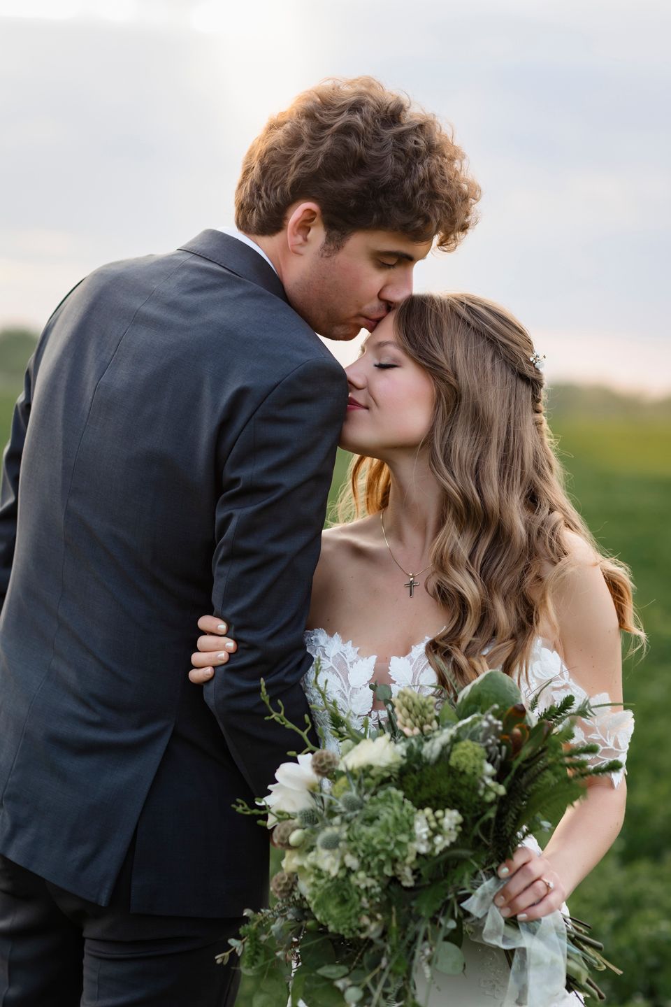 Intimate wedding portrait with tender moment between newlyweds holding a fresh bouquet in Minnesota.
