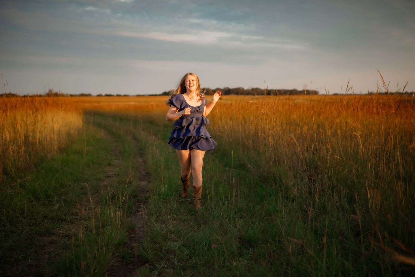 A figure dances through a golden field at sunset wearing a flowing dress.