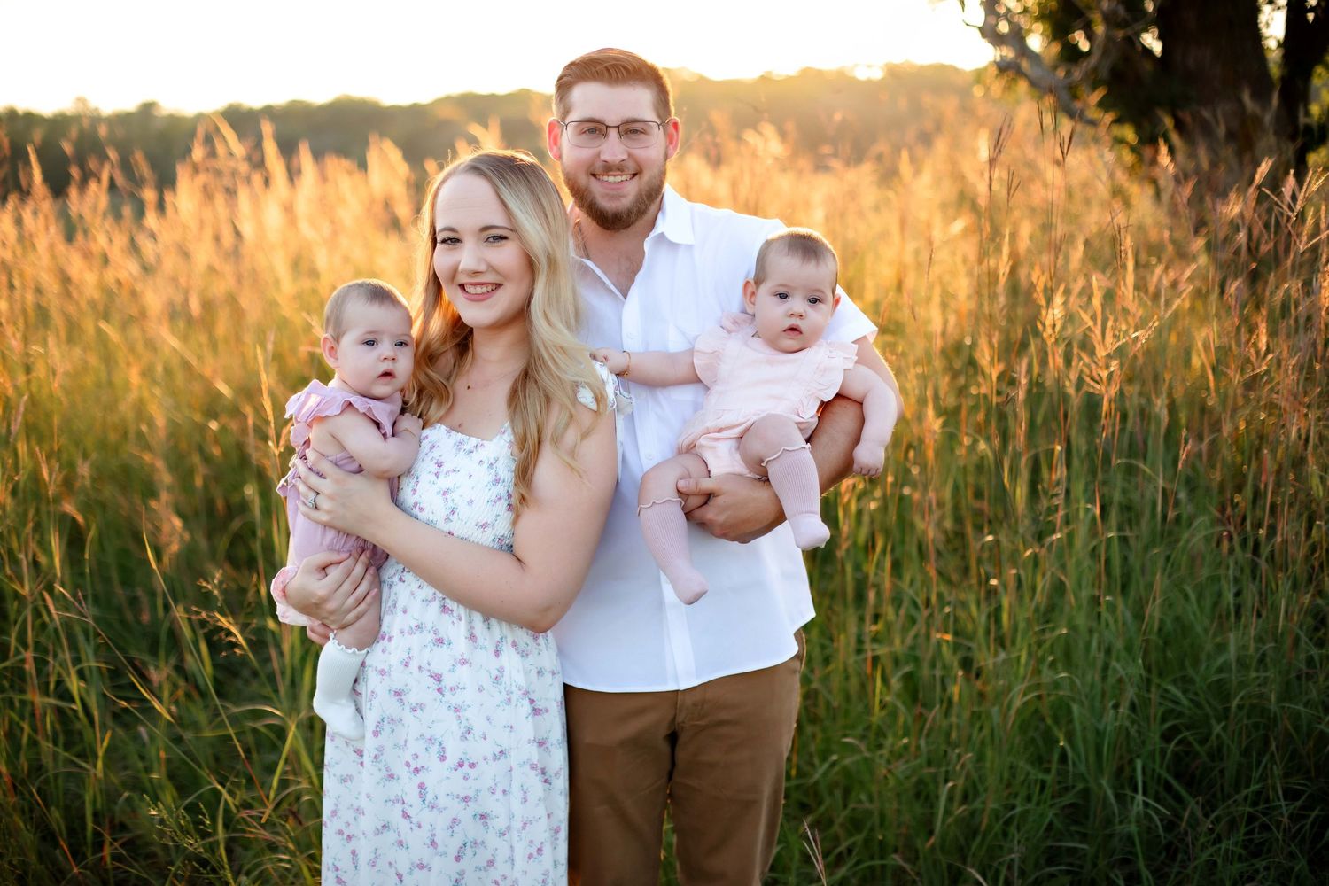 Beautiful sunset family photo in tall grass field with twin infants.
