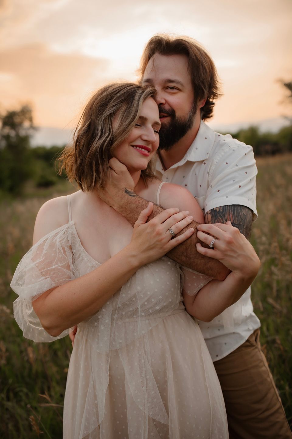 Romantic couple embraces in ethereal evening light surrounded by wildflowers.