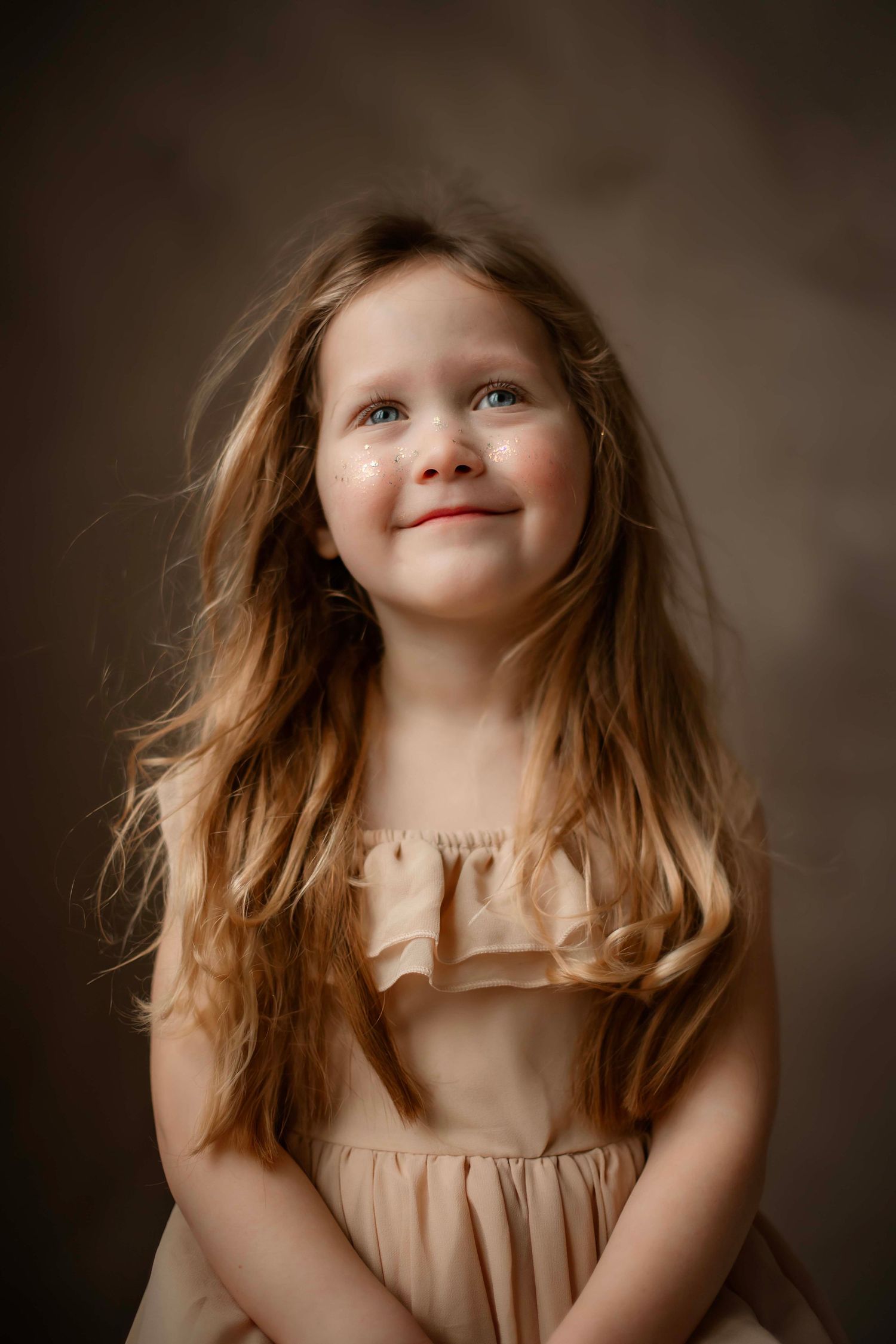 A series of portrait photos showing a child with flowing brown hair in a beige dress against a dark background.