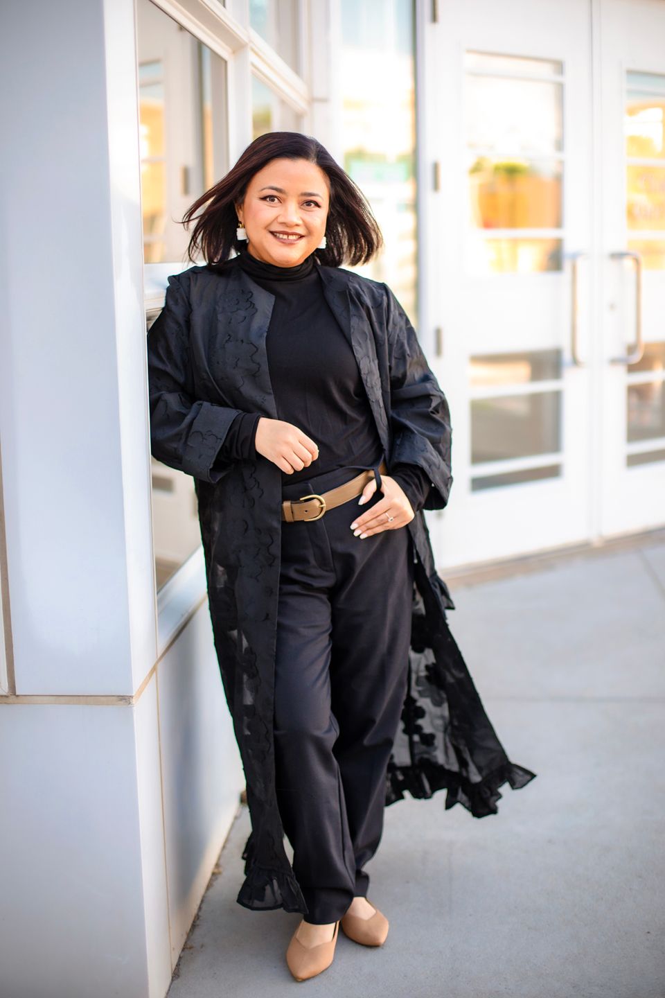 A person wearing all black clothing poses in different positions along a white columned walkway.