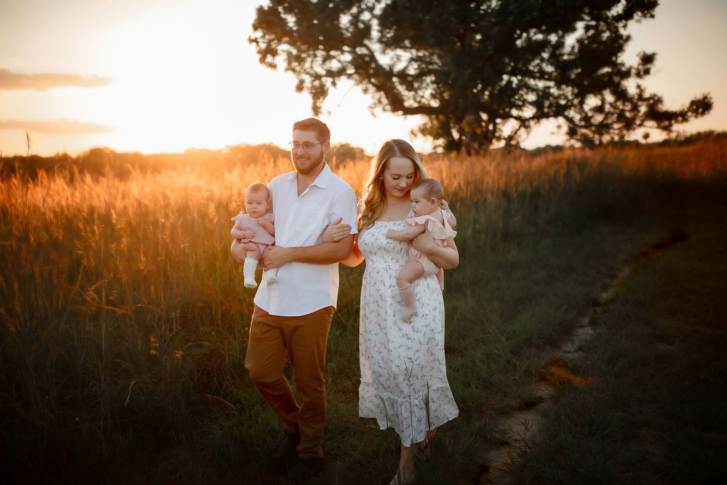 A couple walks together through a golden field at sunset.