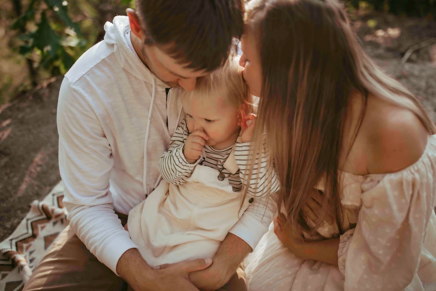 An intimate family portrait with soft lighting and neutral tones in a forest setting.