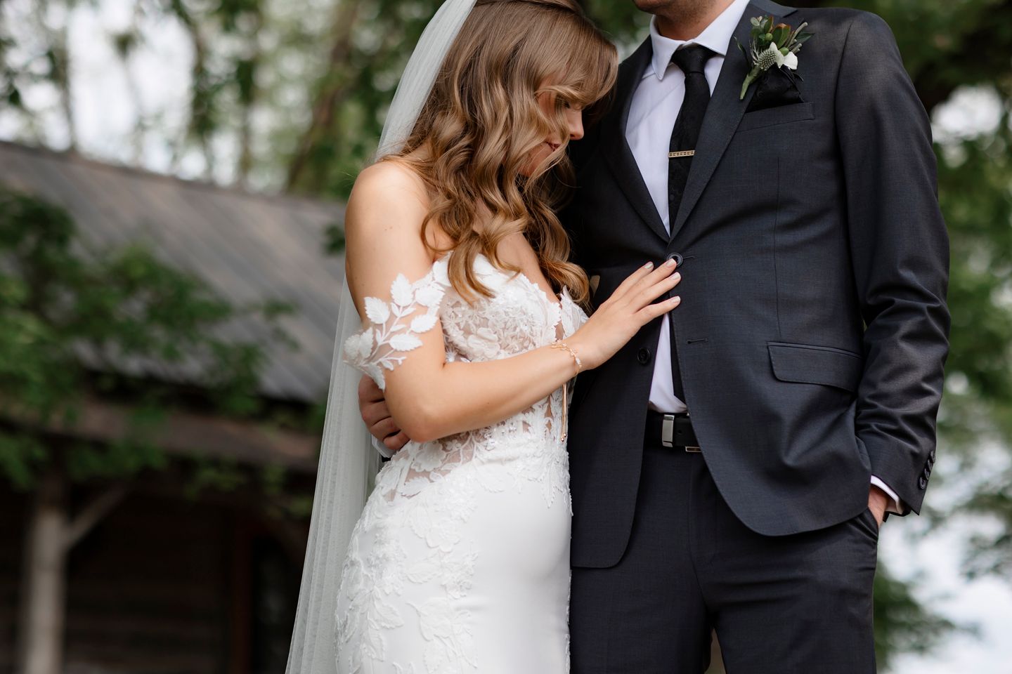 Intimate moment captured between newlyweds showing detailed lace wedding gown and classic tuxedo.