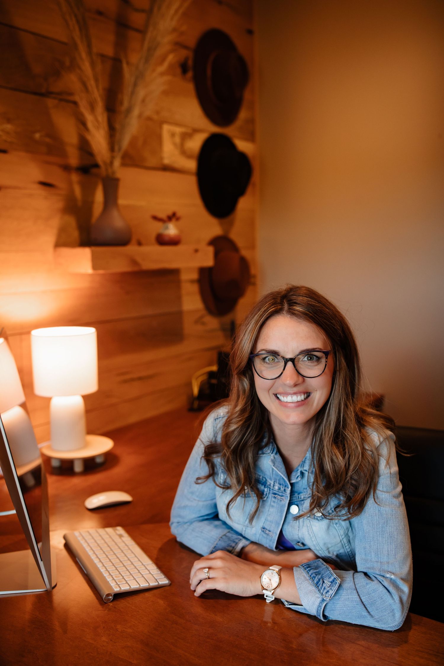 Professional workspace with a wooden accent wall, desk setup with computer and warm lighting.