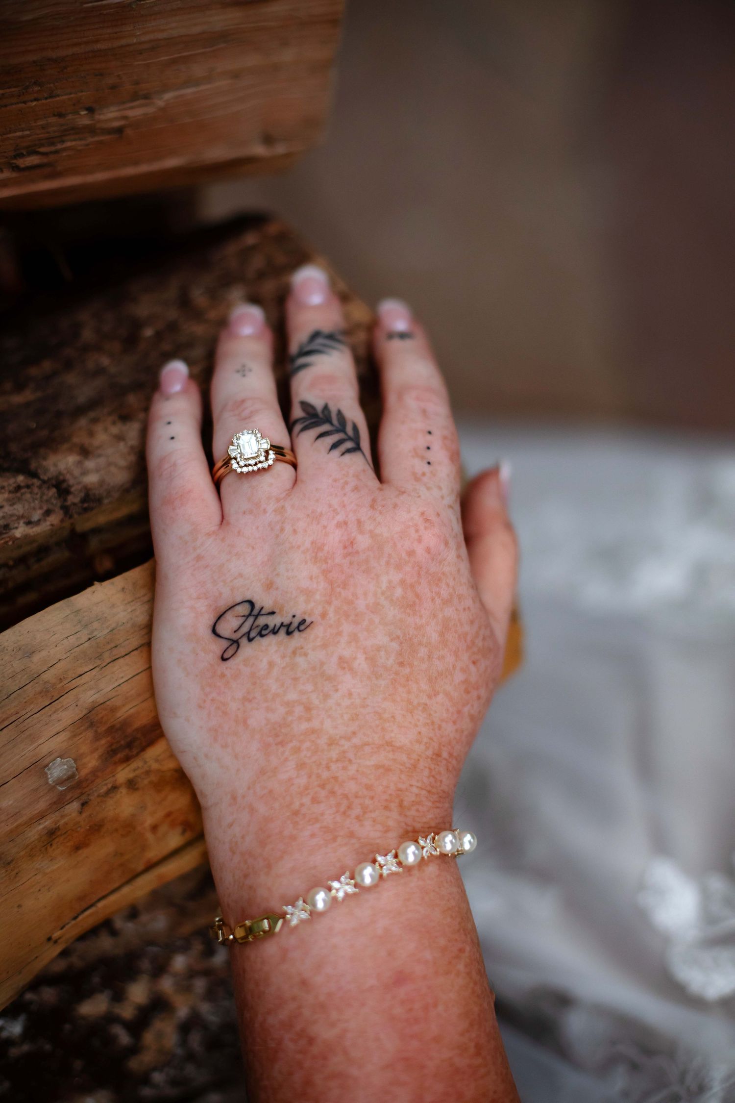 Series of detailed shots showing wedding rings, tattoos and jewelry on hands resting against wooden surface.