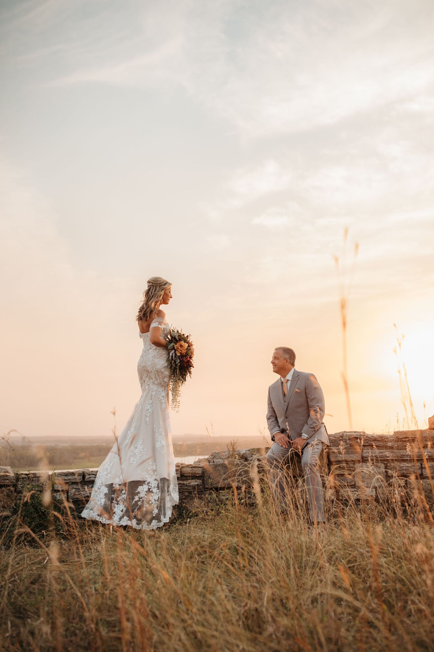 Wedding couple shares romantic moment on hillside during golden hour.