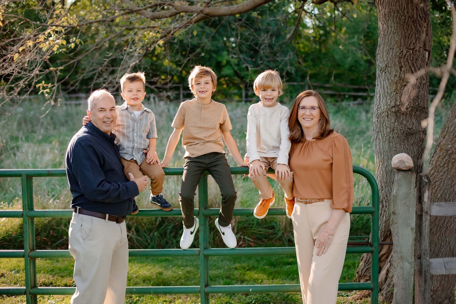 Family group posing by green railing in outdoor park setting.