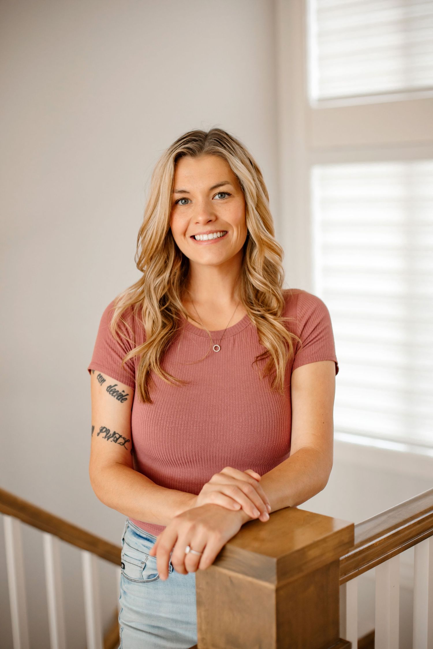 Casual indoor portrait wearing pink ribbed t-shirt and light wash denim.
