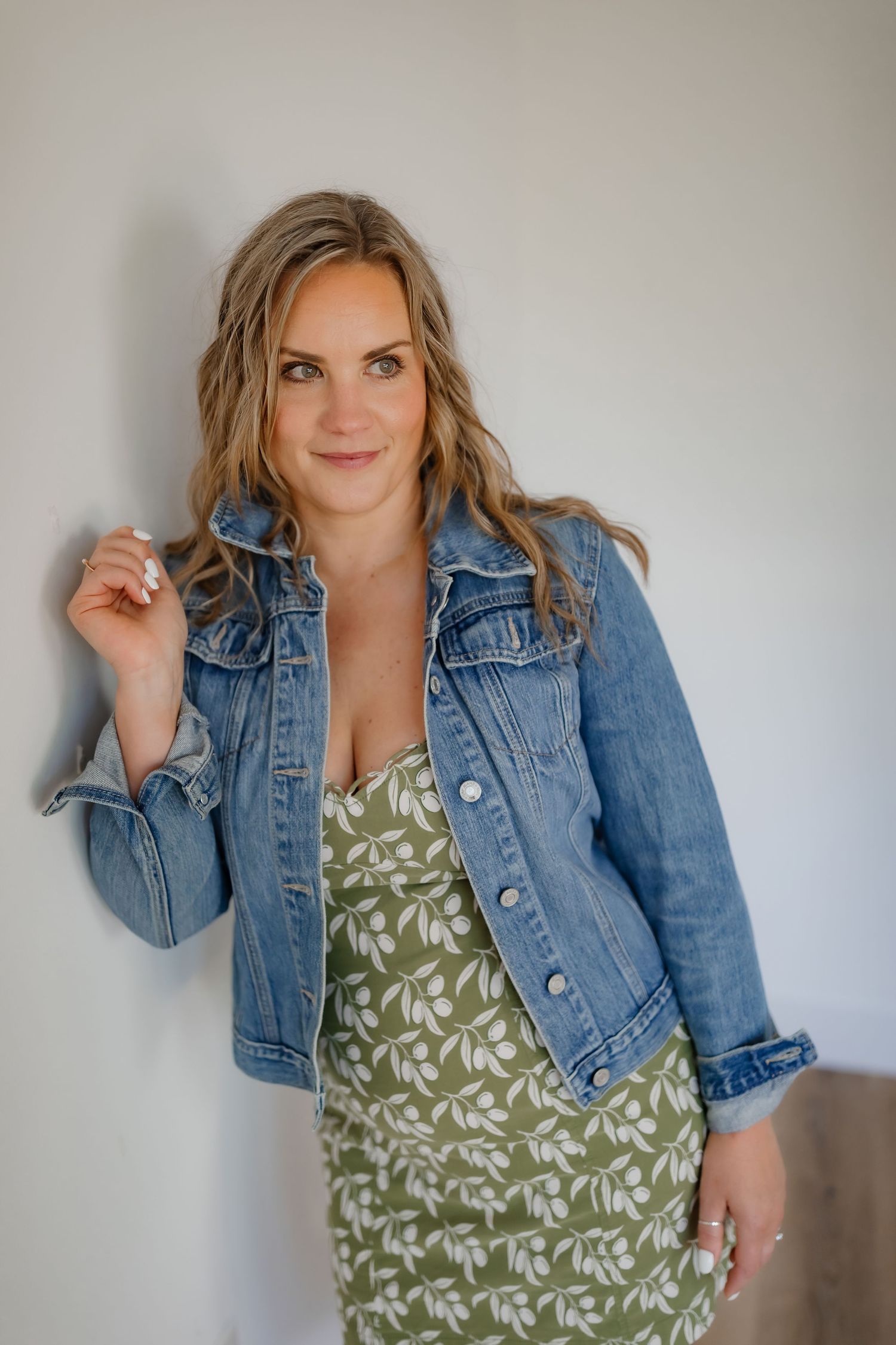 Stylish casual look featuring a denim jacket paired with a green patterned dress against a neutral background.