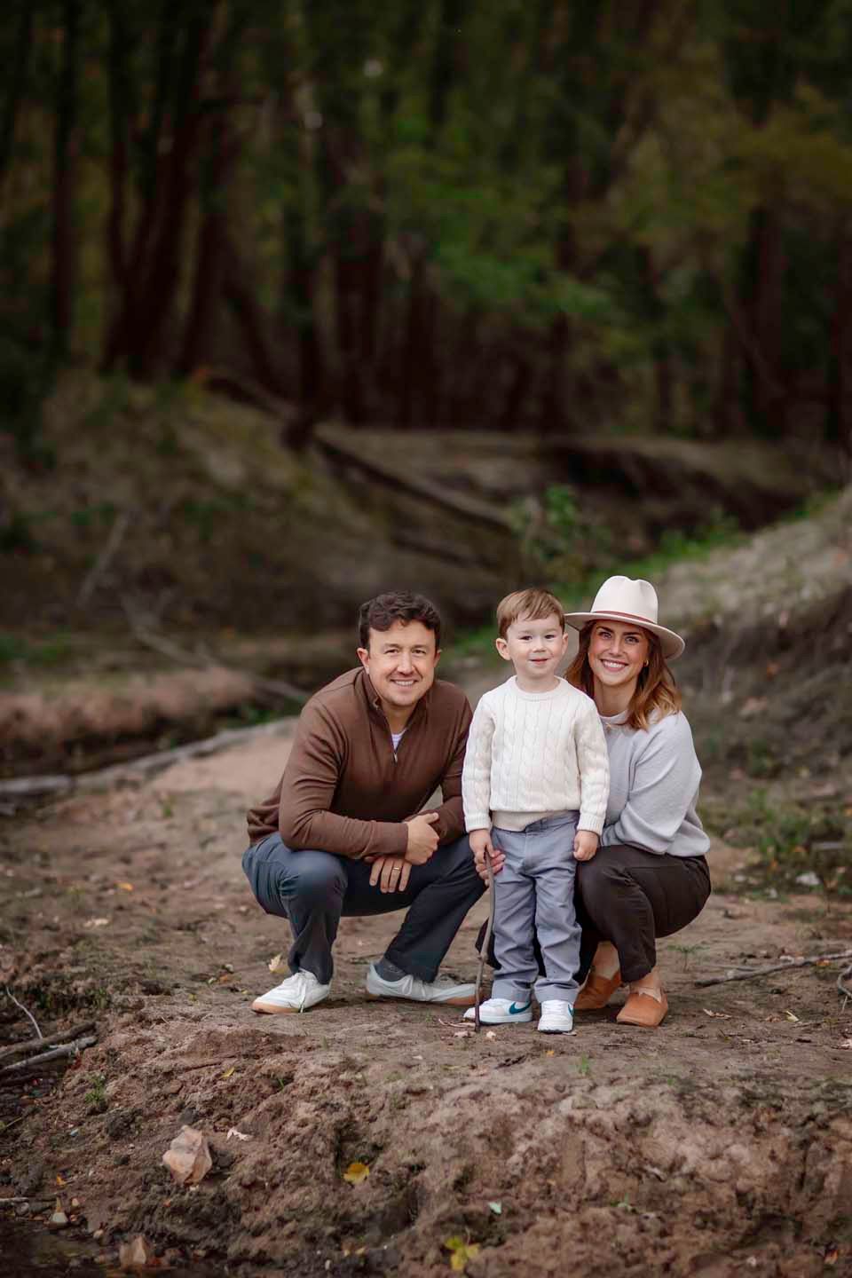 A casual outdoor family portrait taken in a forest setting.