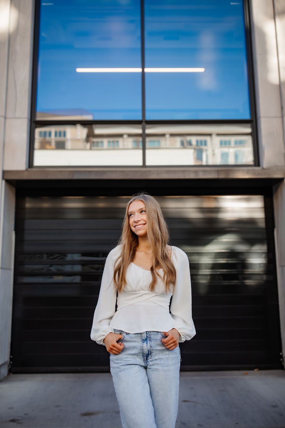 Casual portrait against modern building with glass windows and architectural details.