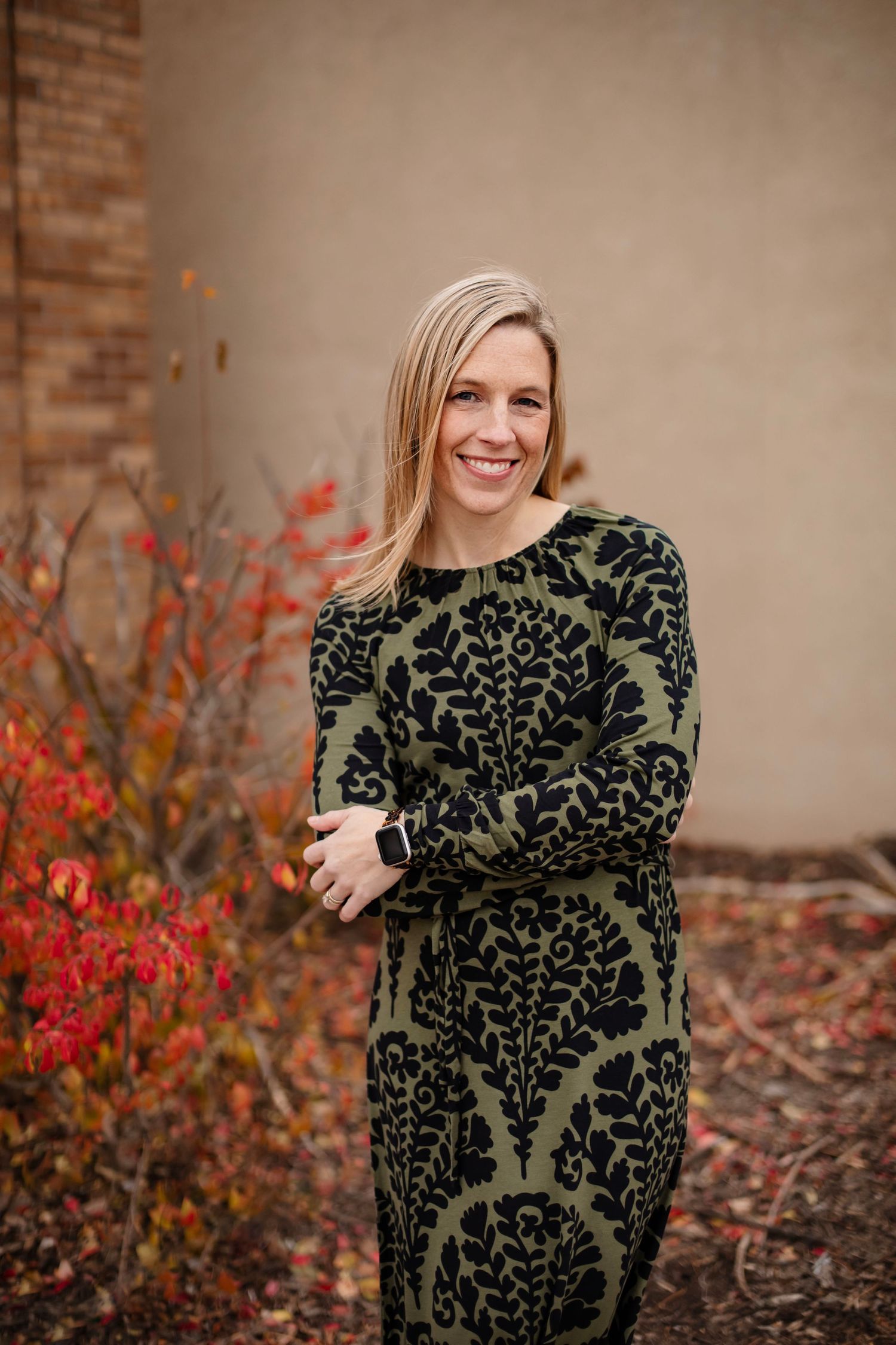 Fall outdoor portrait wearing olive damask dress with red autumn leaves in background.