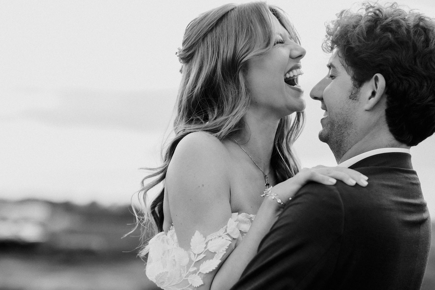 Black and white candid moment of joy between newlyweds sharing laughter.