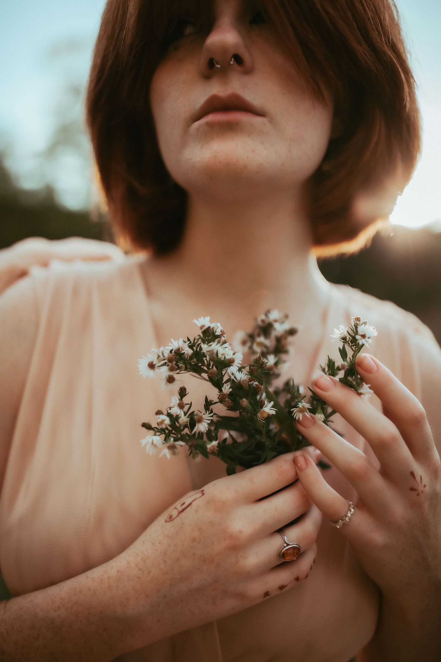 Delicate white flowers held against a peach-colored dress in soft sunset lighting.