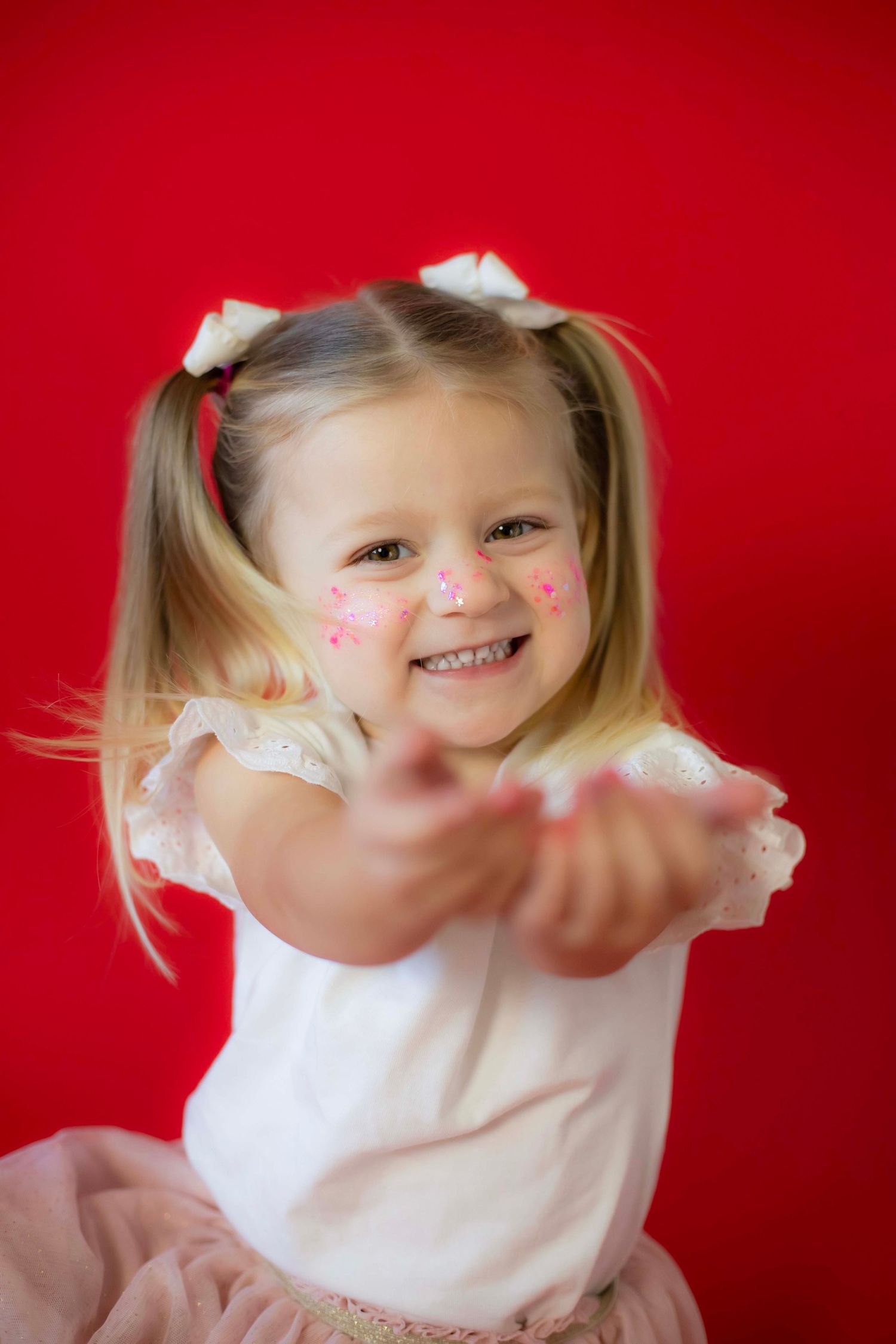 Playful moment with glitter makeup against bright red background.