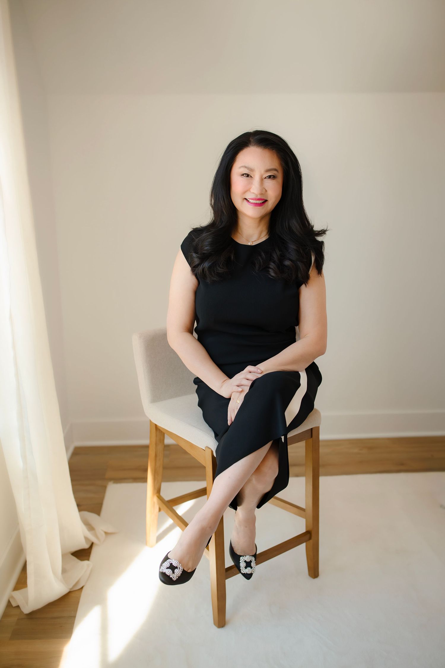 Three casual poses of a person sitting in a wooden chair wearing a black outfit with natural lighting.