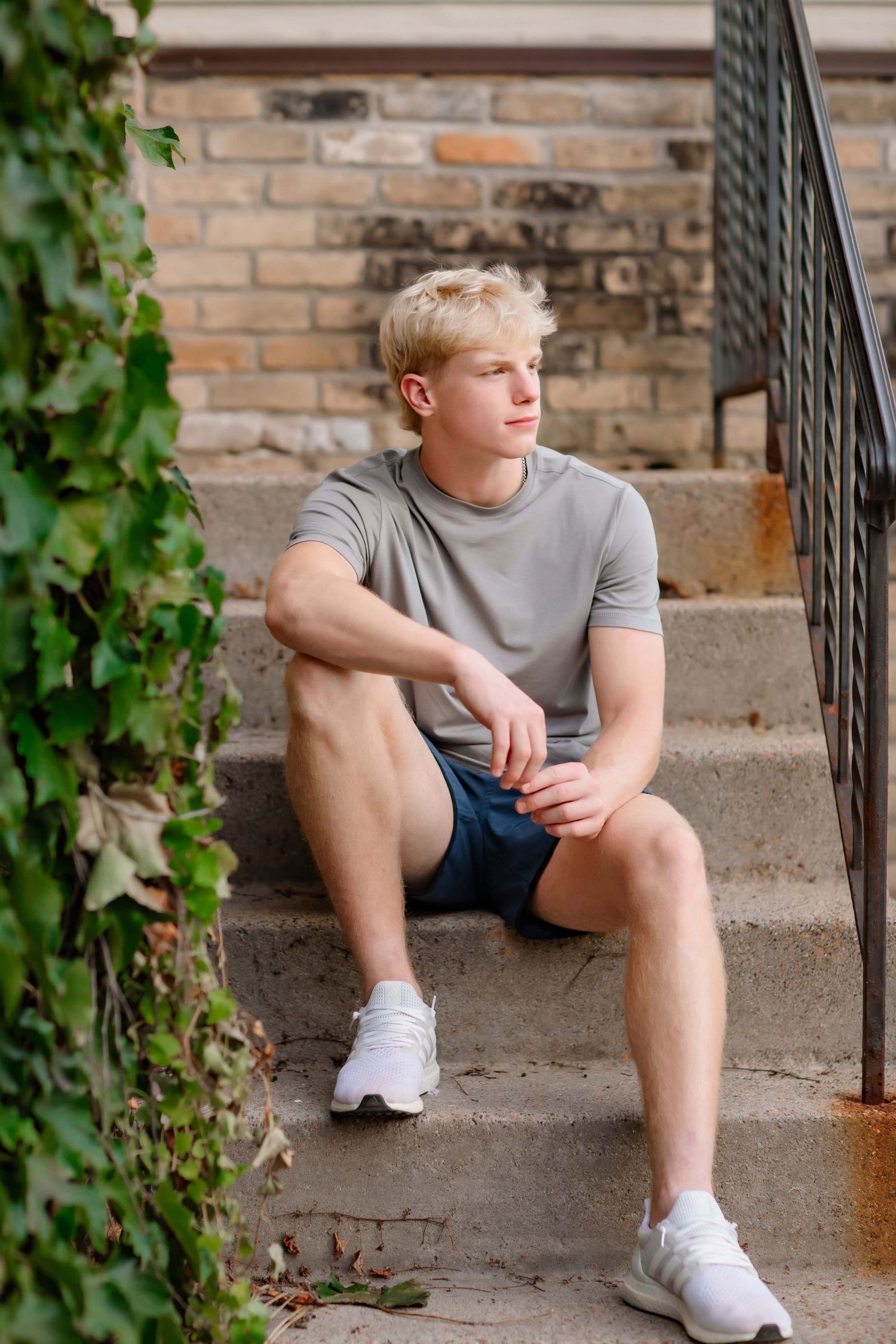 Person sitting on brick steps with ivy growing nearby wearing athletic wear.