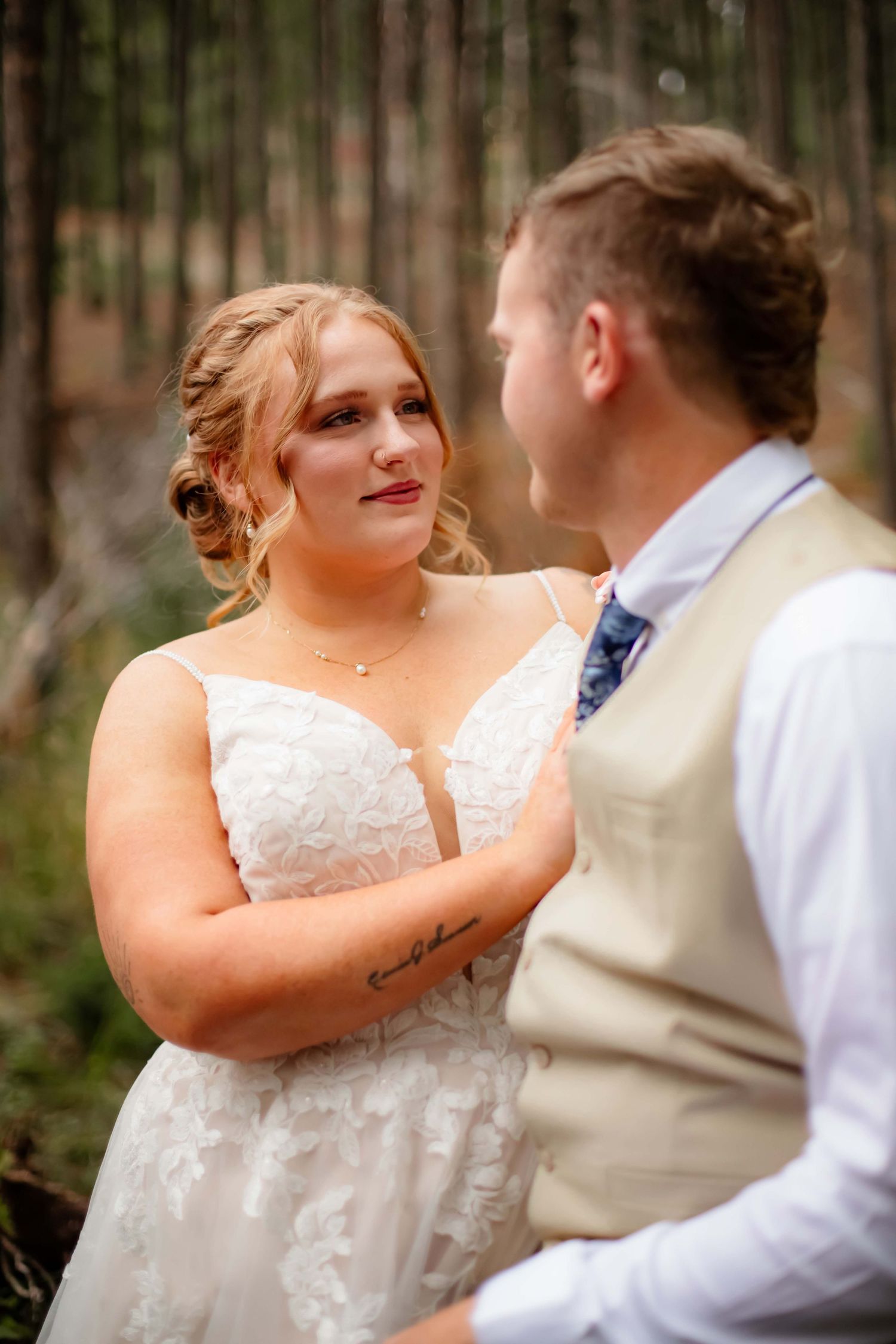 A romantic moment captured between newlyweds in a wooded forest setting.