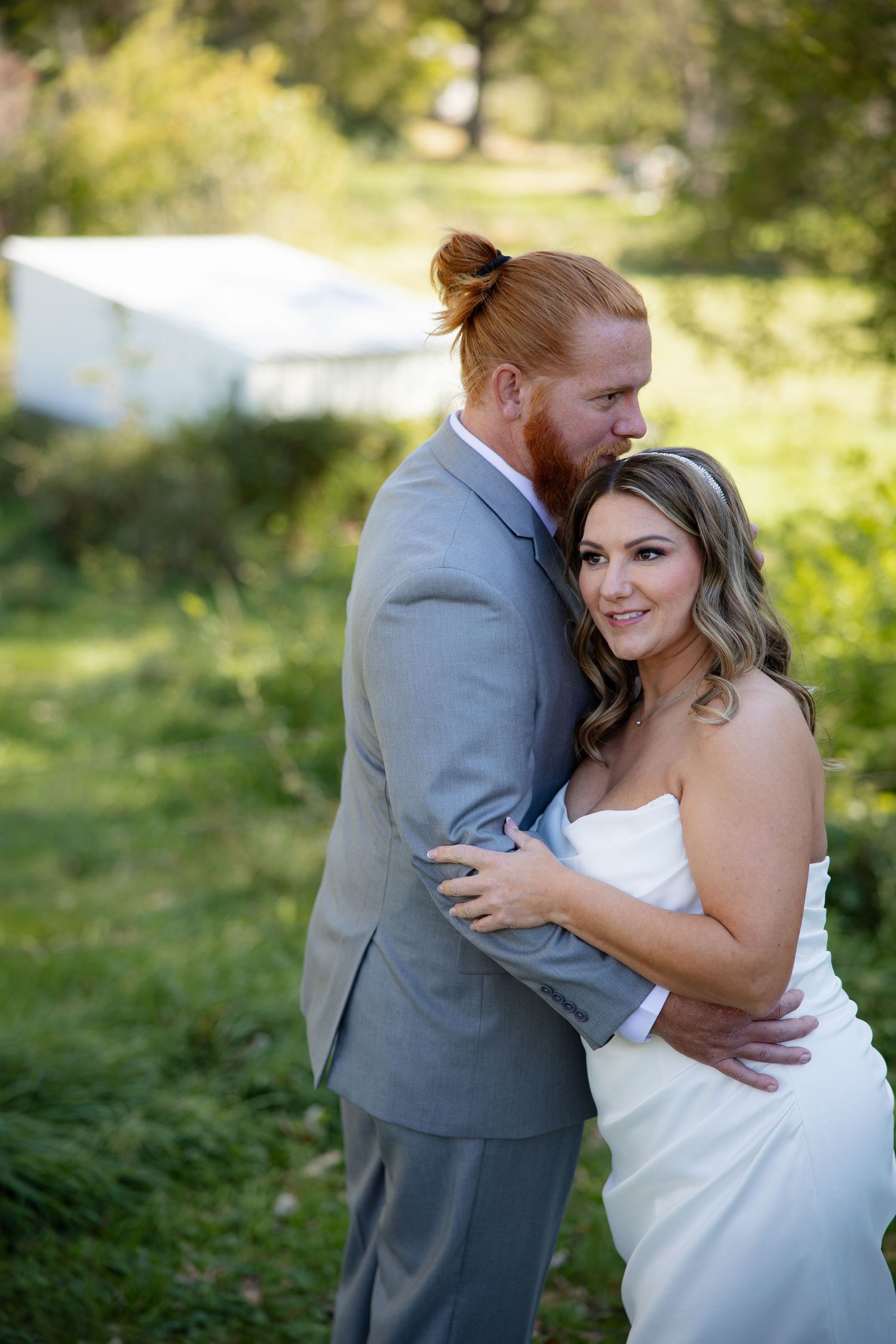 A romantic wedding portrait of a couple embracing outdoors in a garden setting.
