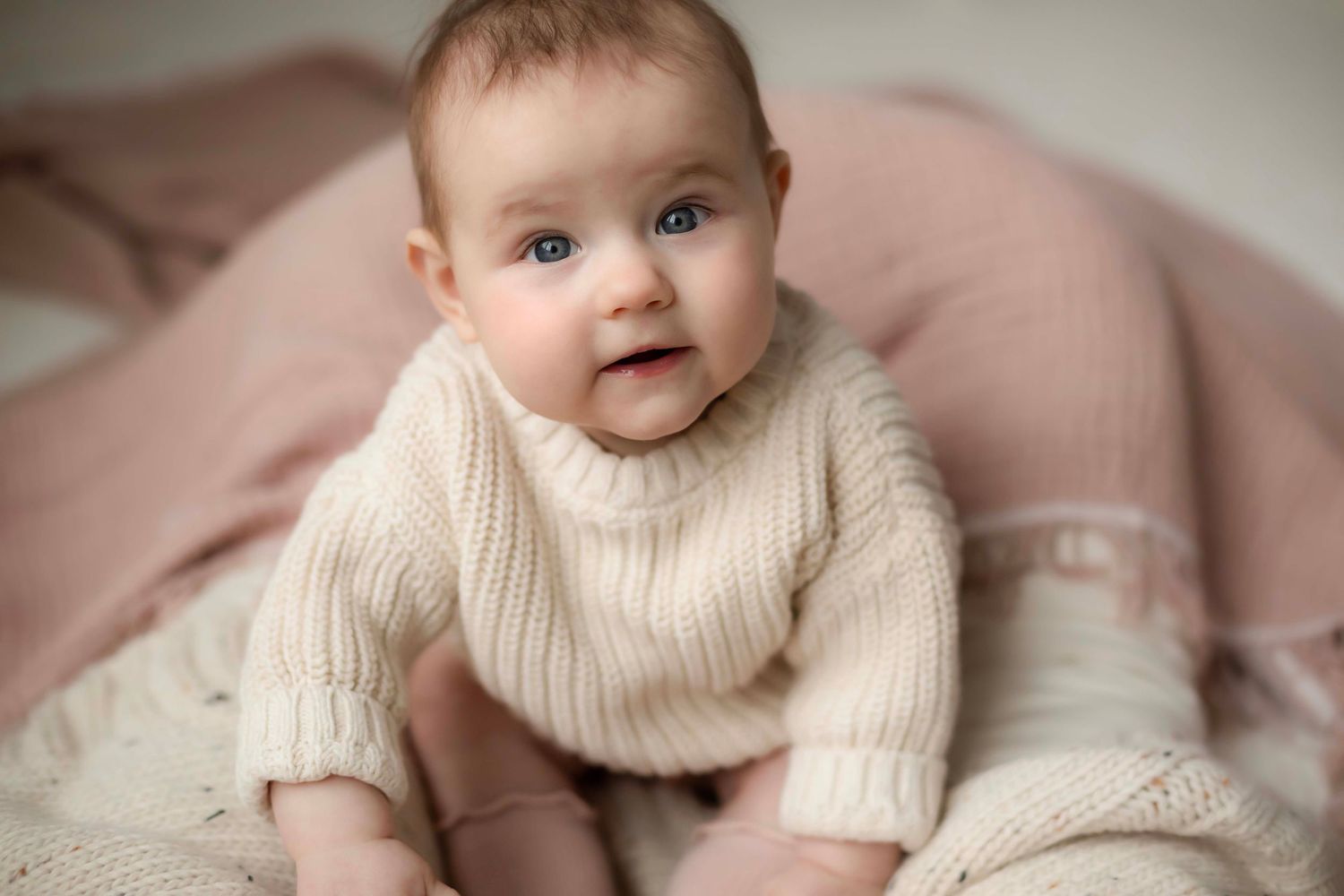 A baby wearing a cream knit sweater with Willow & Wren Photography
