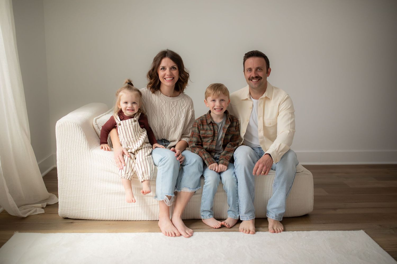 A cozy family portrait session on a white couch showing casual poses and warm interactions.