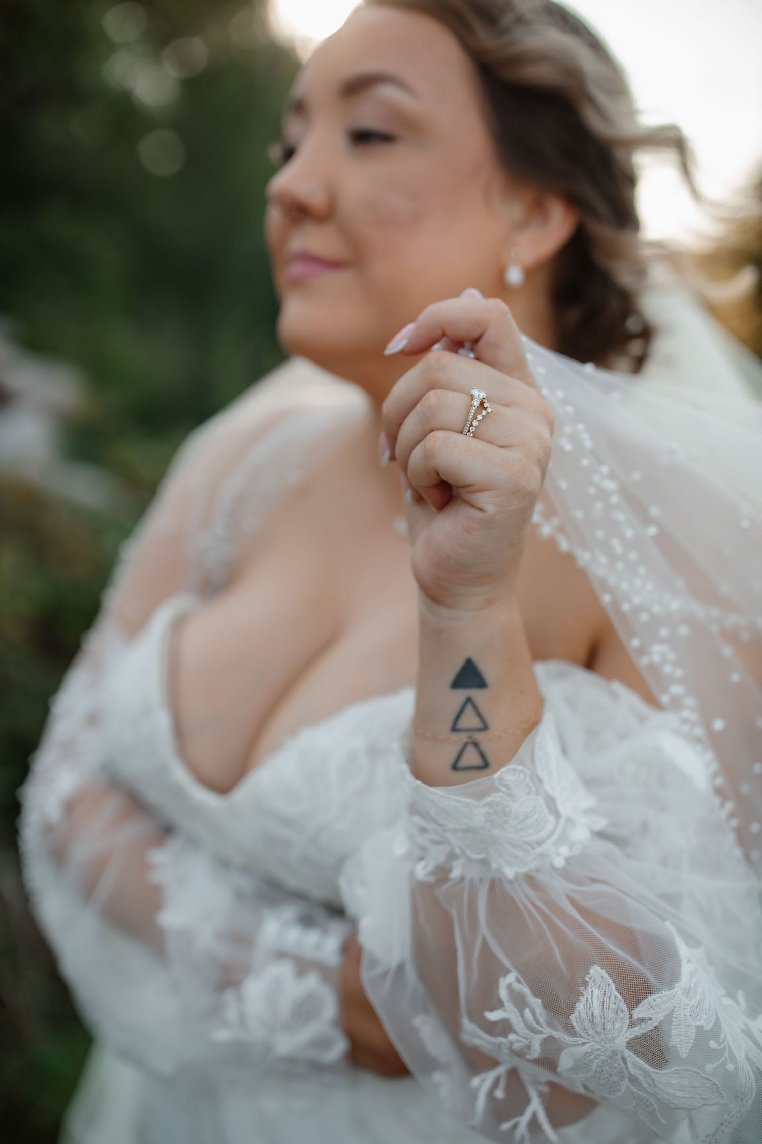 Close up of bridal details showing geometric triangle tattoo and lace sleeve wedding dress.