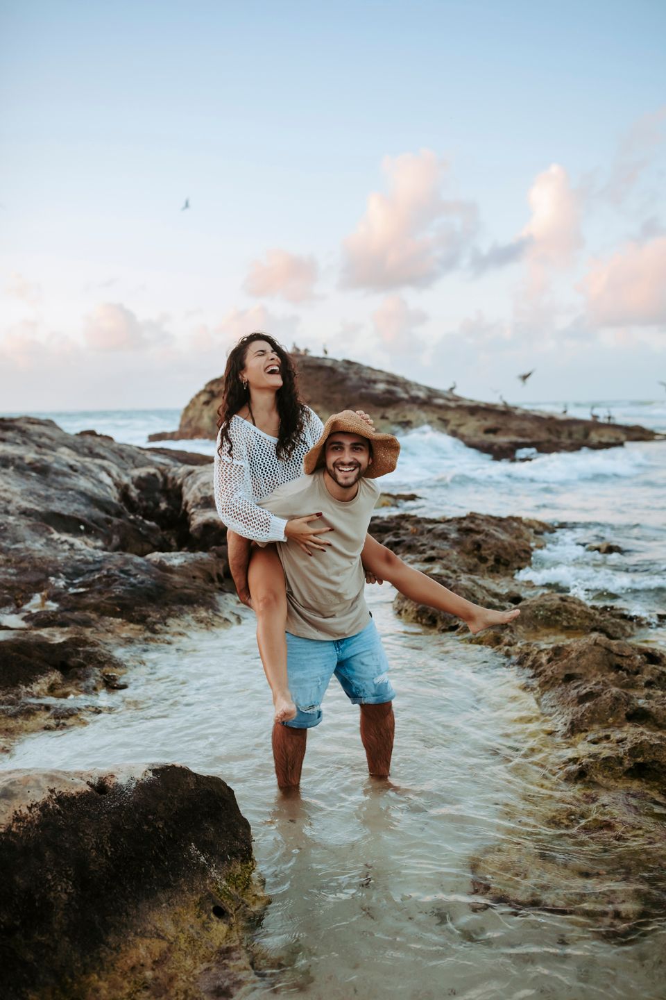A joyful piggyback ride along the rocky shoreline during golden hour.