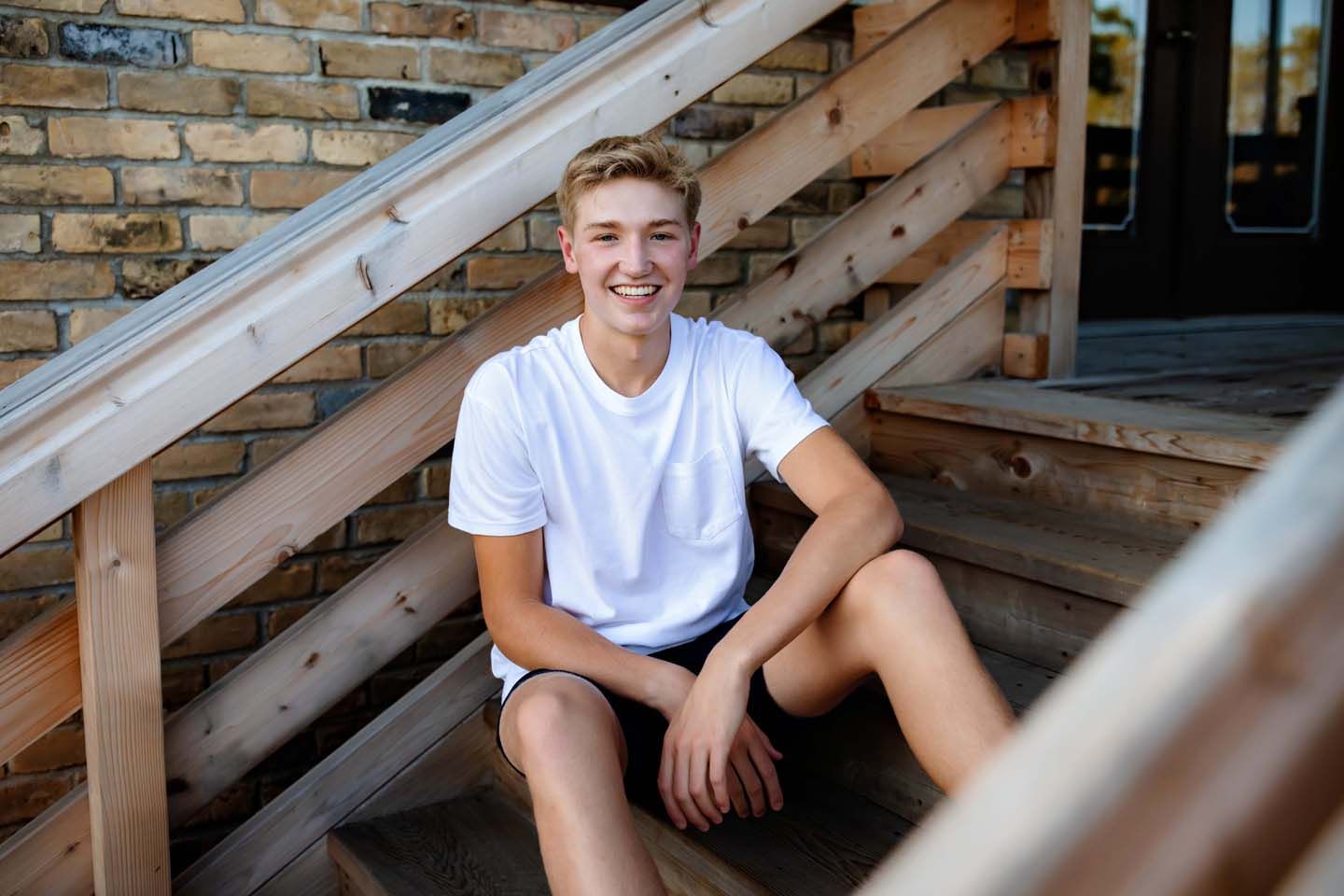 Natural lifestyle portrait on wooden stairs with casual summer attire.