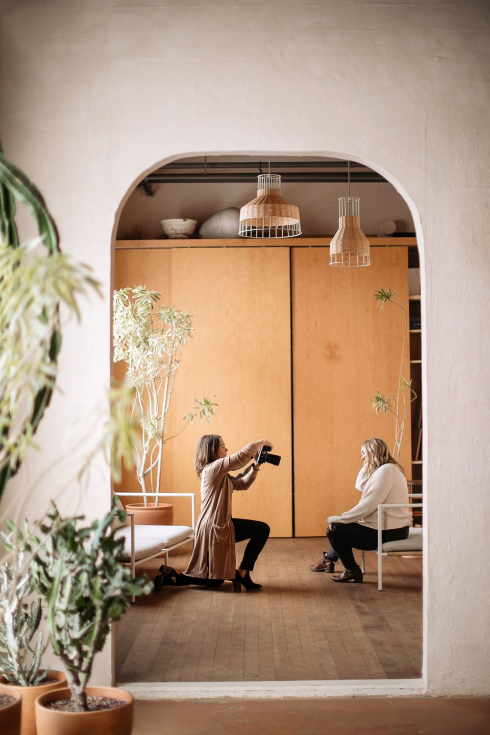 A behind-the-scenes view through an archway of photographers at work in a minimalist setting.
