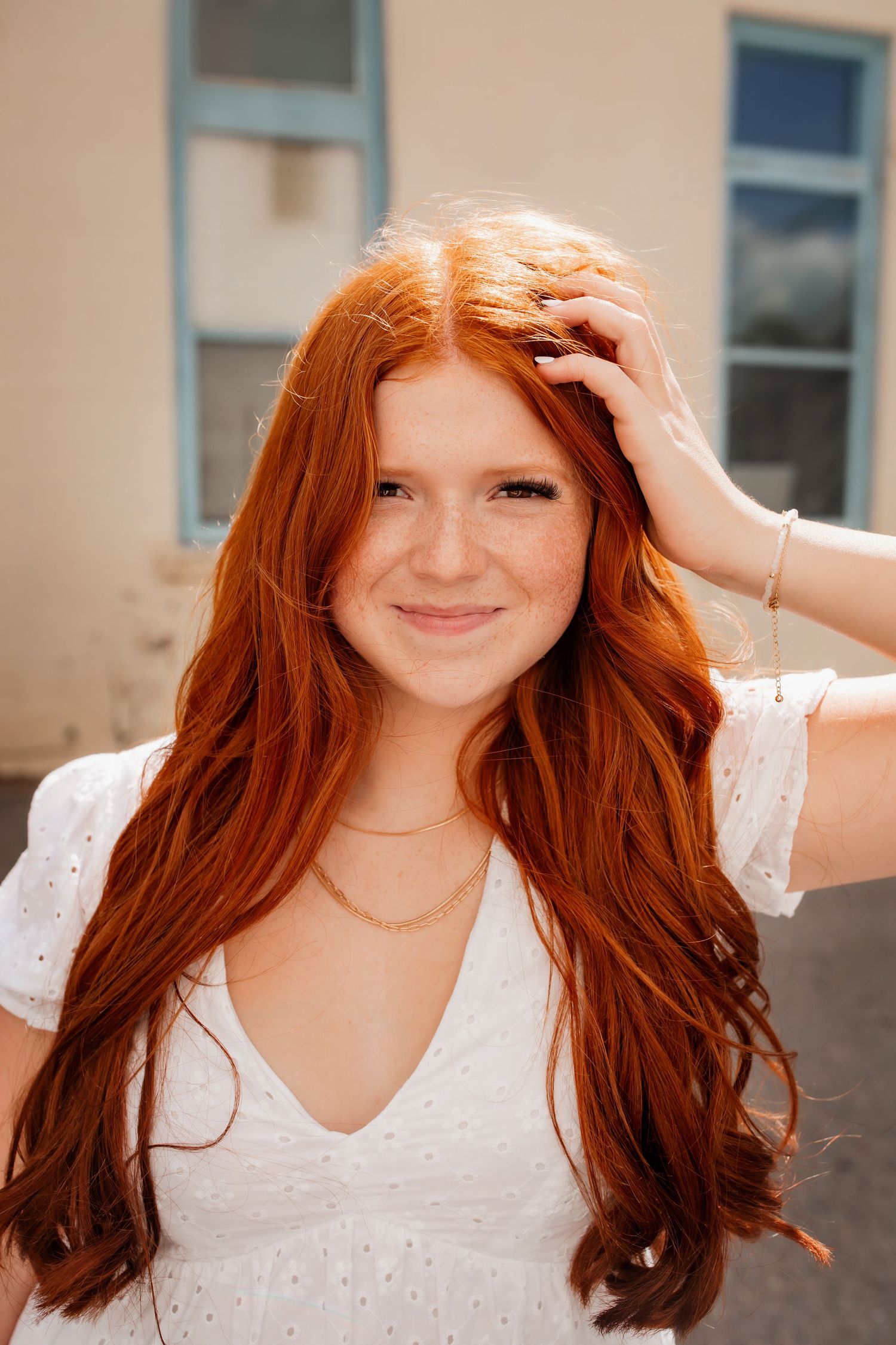 Stunning copper-colored hair shown against creamy building exterior.