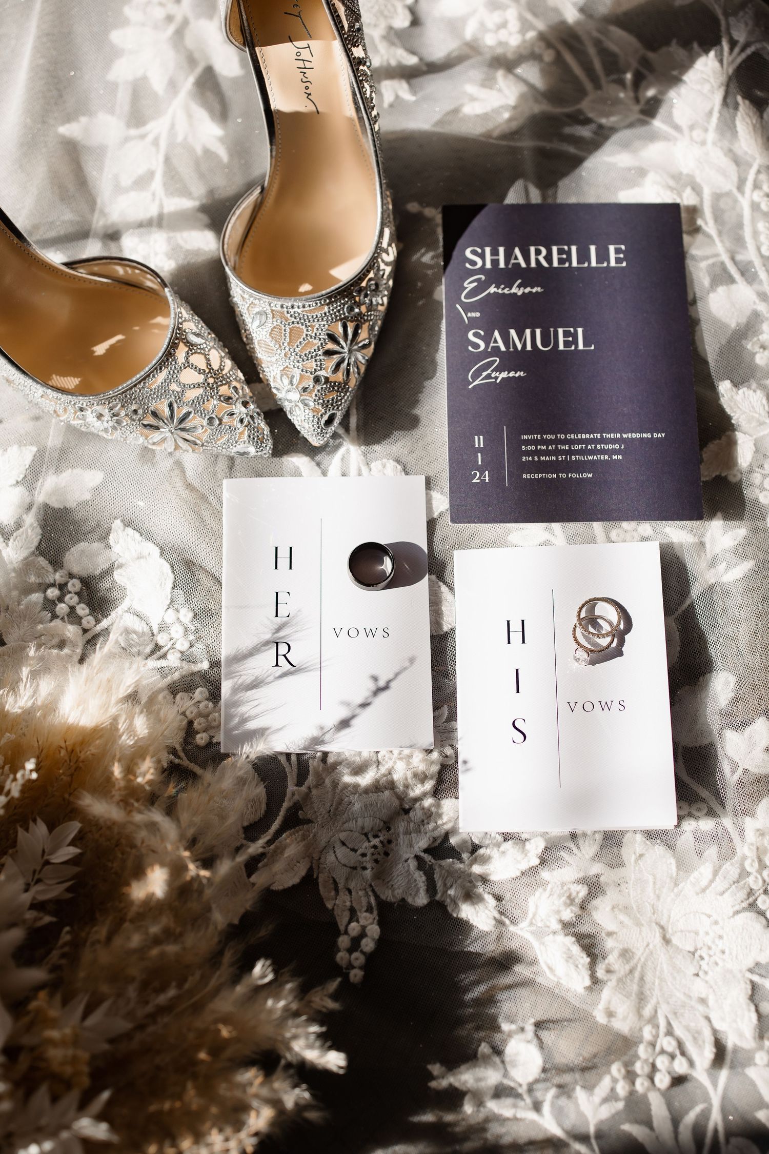 Elegant bridal shoes and wedding invitation suite displayed on textured white fabric.