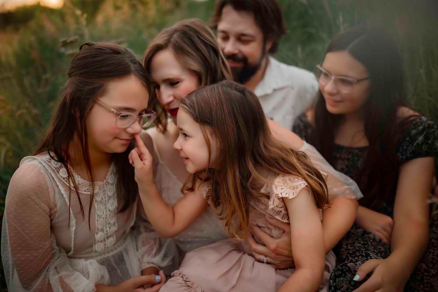 Group shares intimate laughing moment together in evening sunlight.