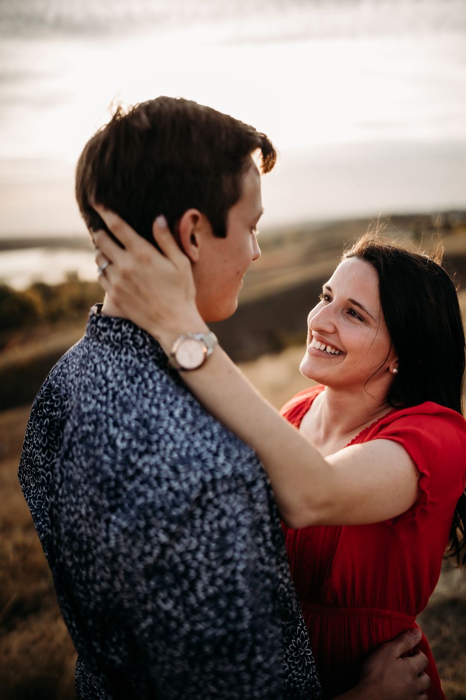 A romantic moment shared between two people in coordinated outfits against a scenic backdrop.