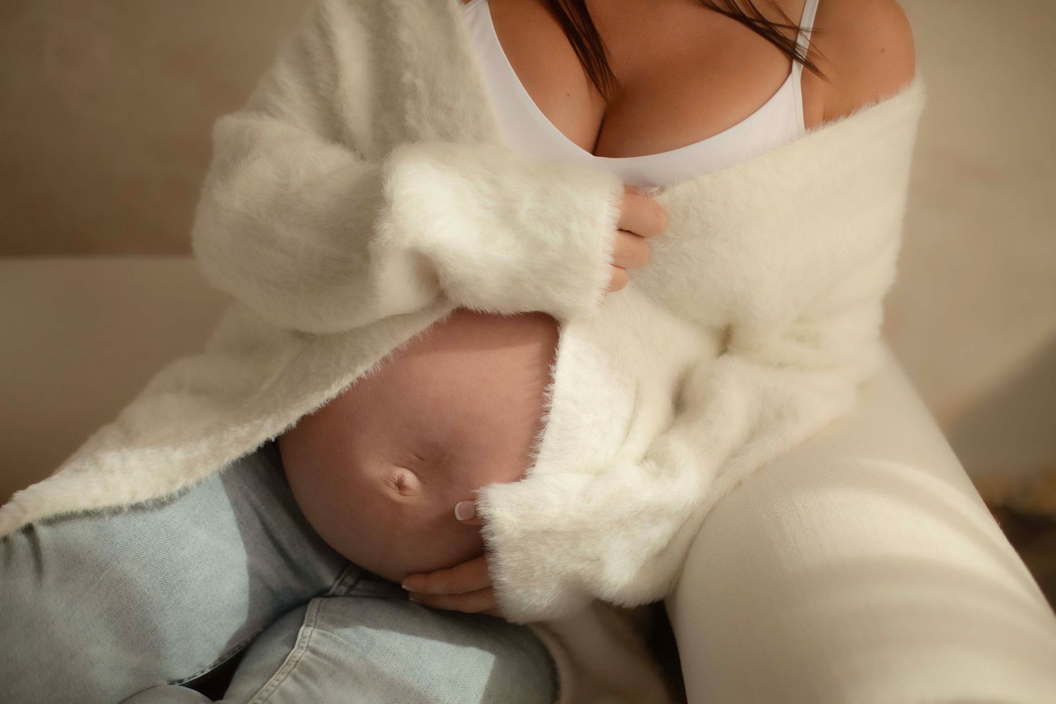 Mother breastfeeding newborn baby wrapped in soft white blanket, intimate nursing moment captured in warm natural light.
