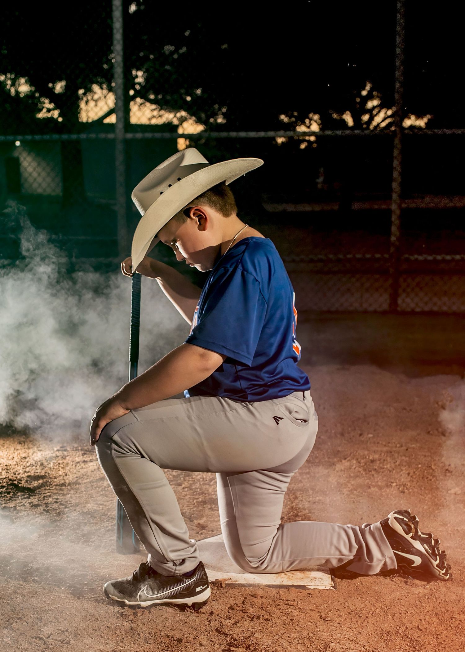 A baseball player in a crouching position with smoke effects and wearing a cowboy hat.