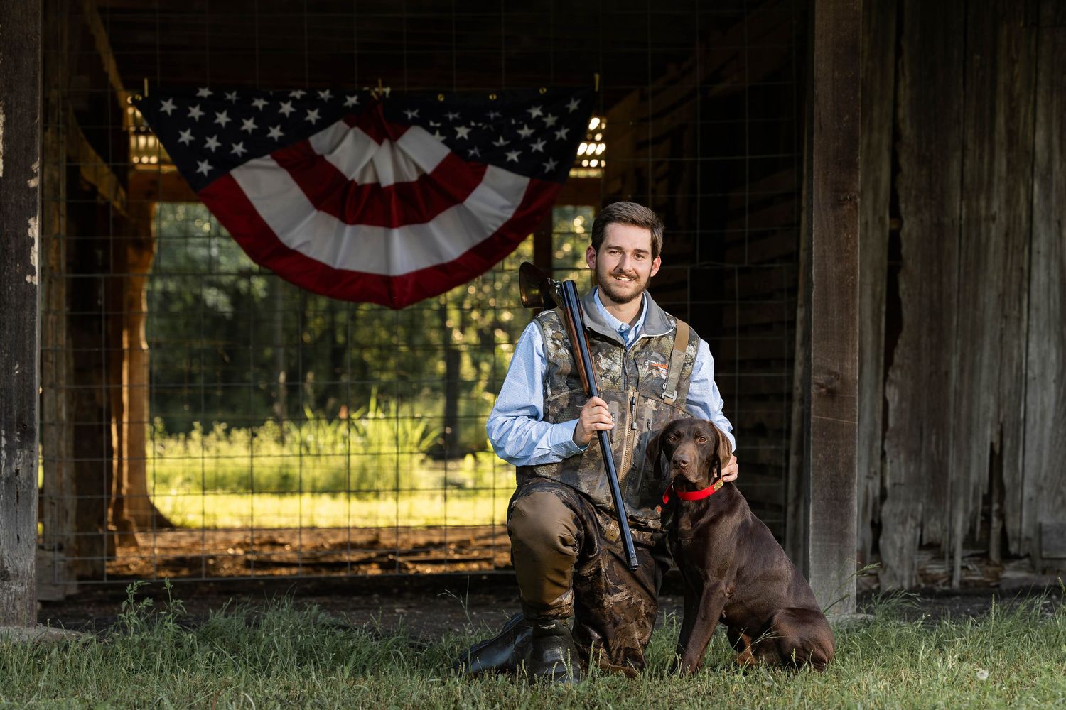 American flag bunting decorates a rustic barn setting with hunting dog and outdoor gear.