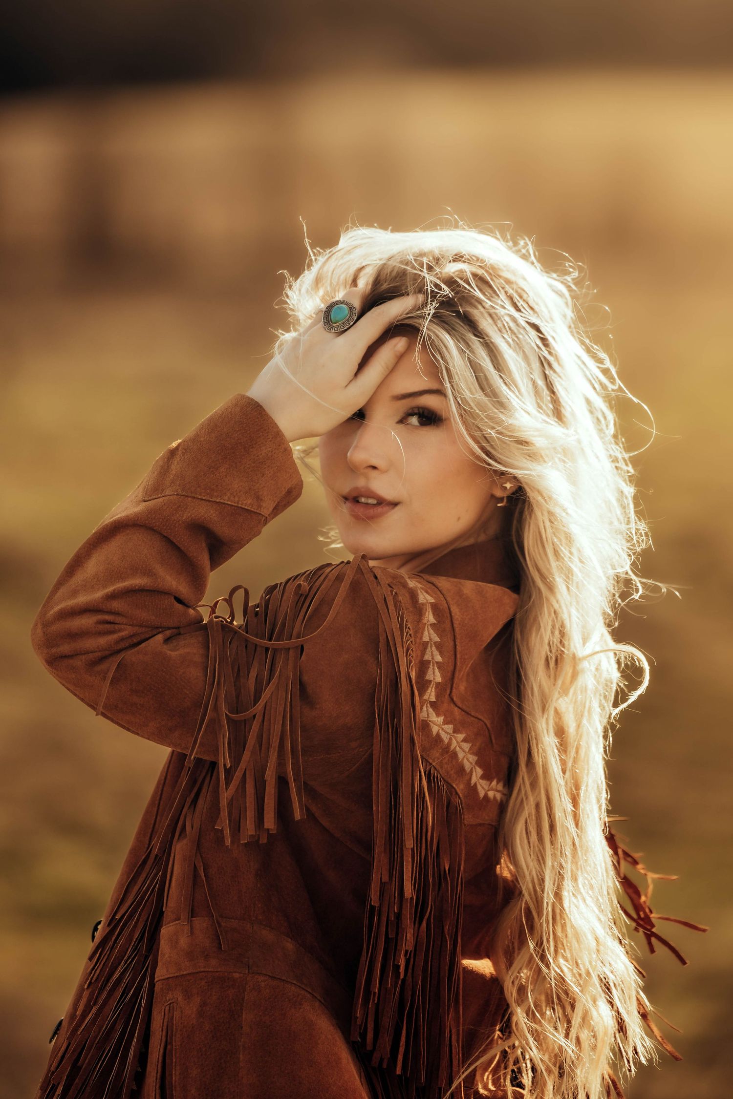 Backlit portrait in brown fringe jacket with golden sunset glow.