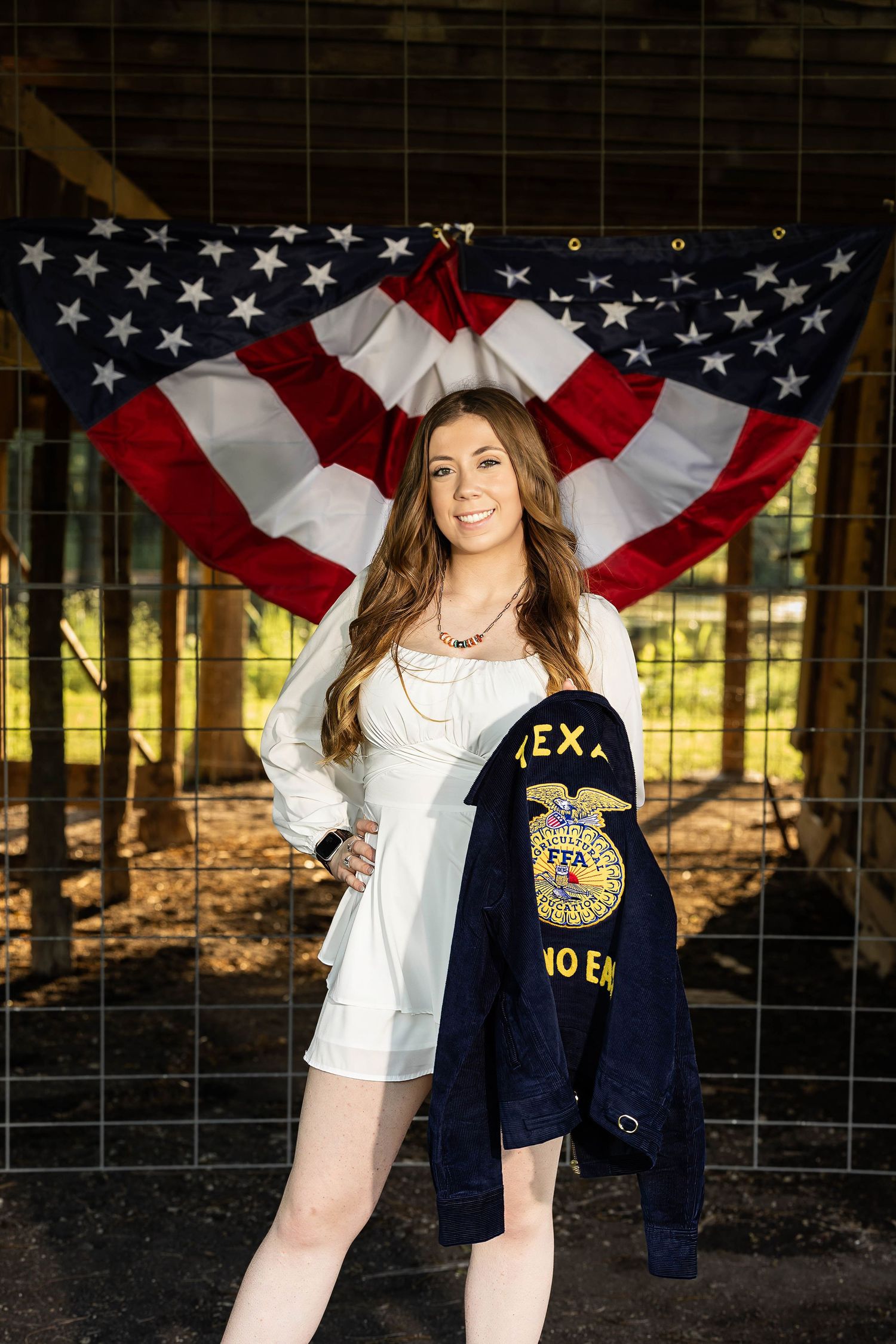 Patriotic backdrop with American flag bunting paired with white dress and FFA jacket.