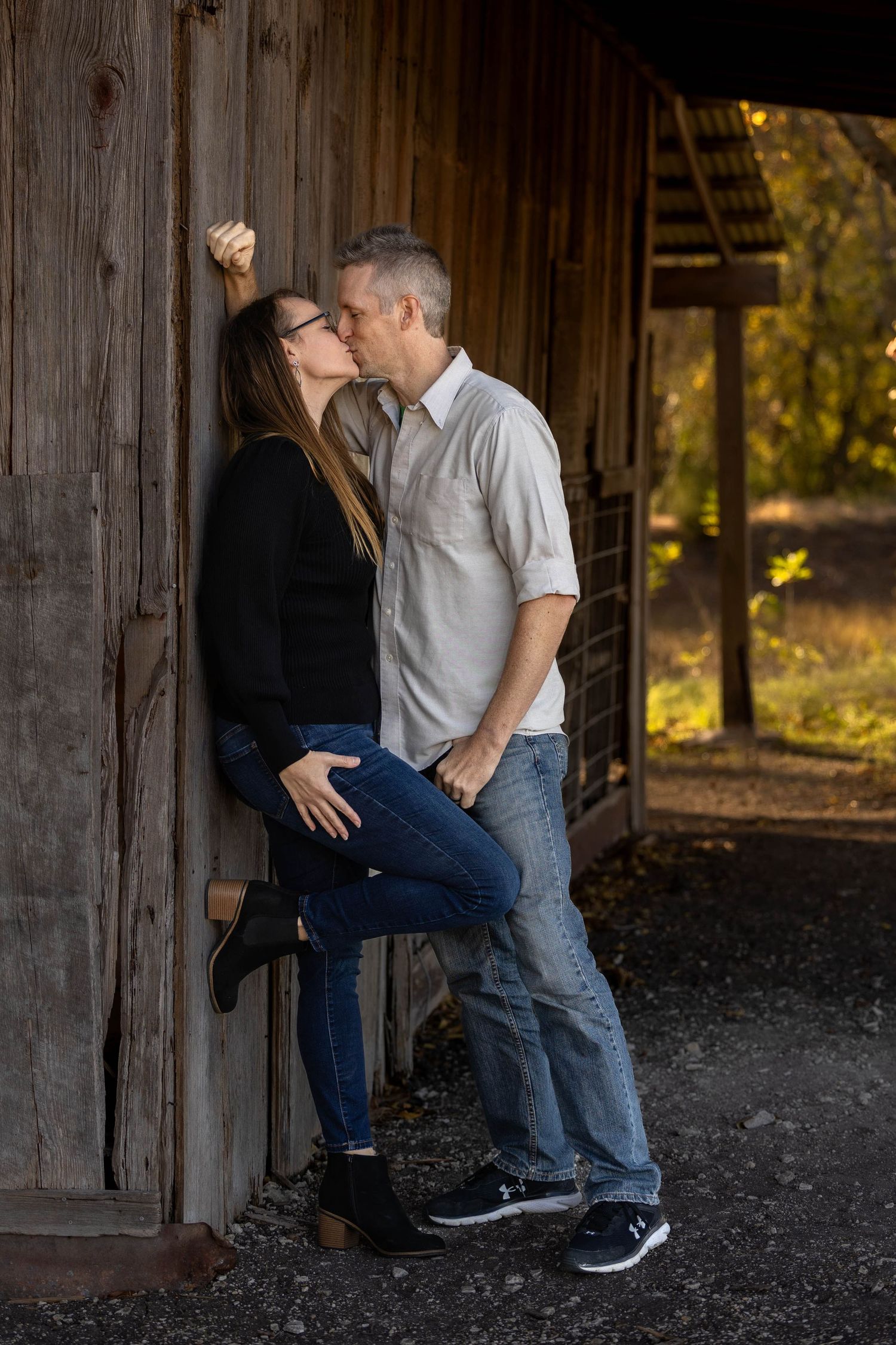 A romantic couple shares an intimate moment against a rustic wooden wall at golden hour.