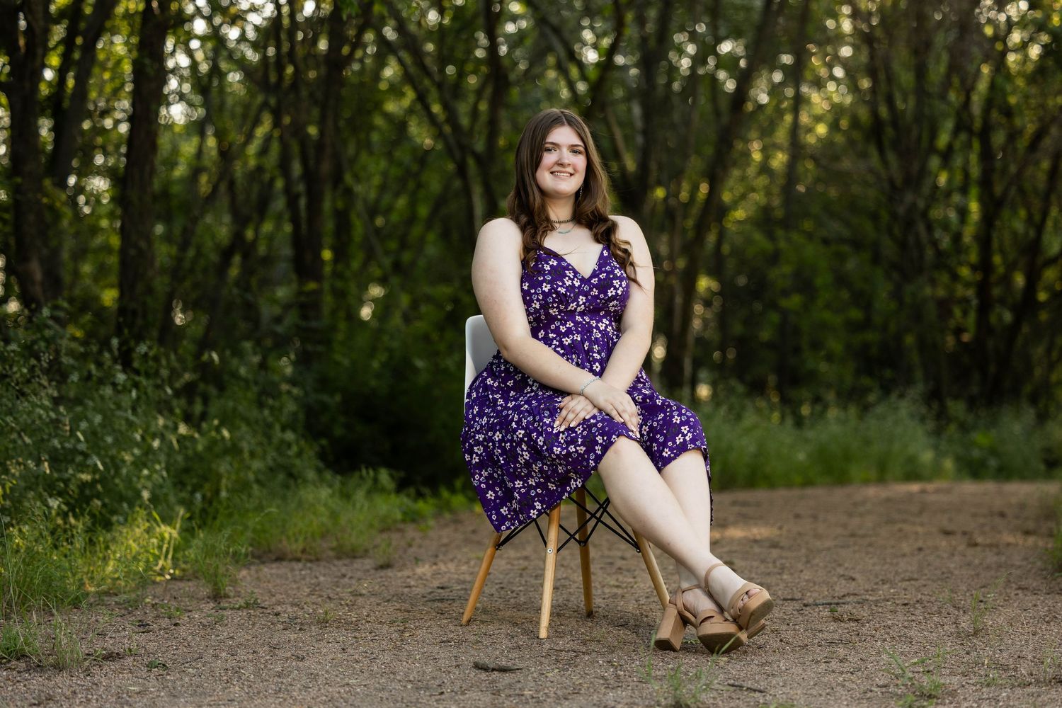 A purple floral dress complements the natural wooded path setting in this outdoor portrait.