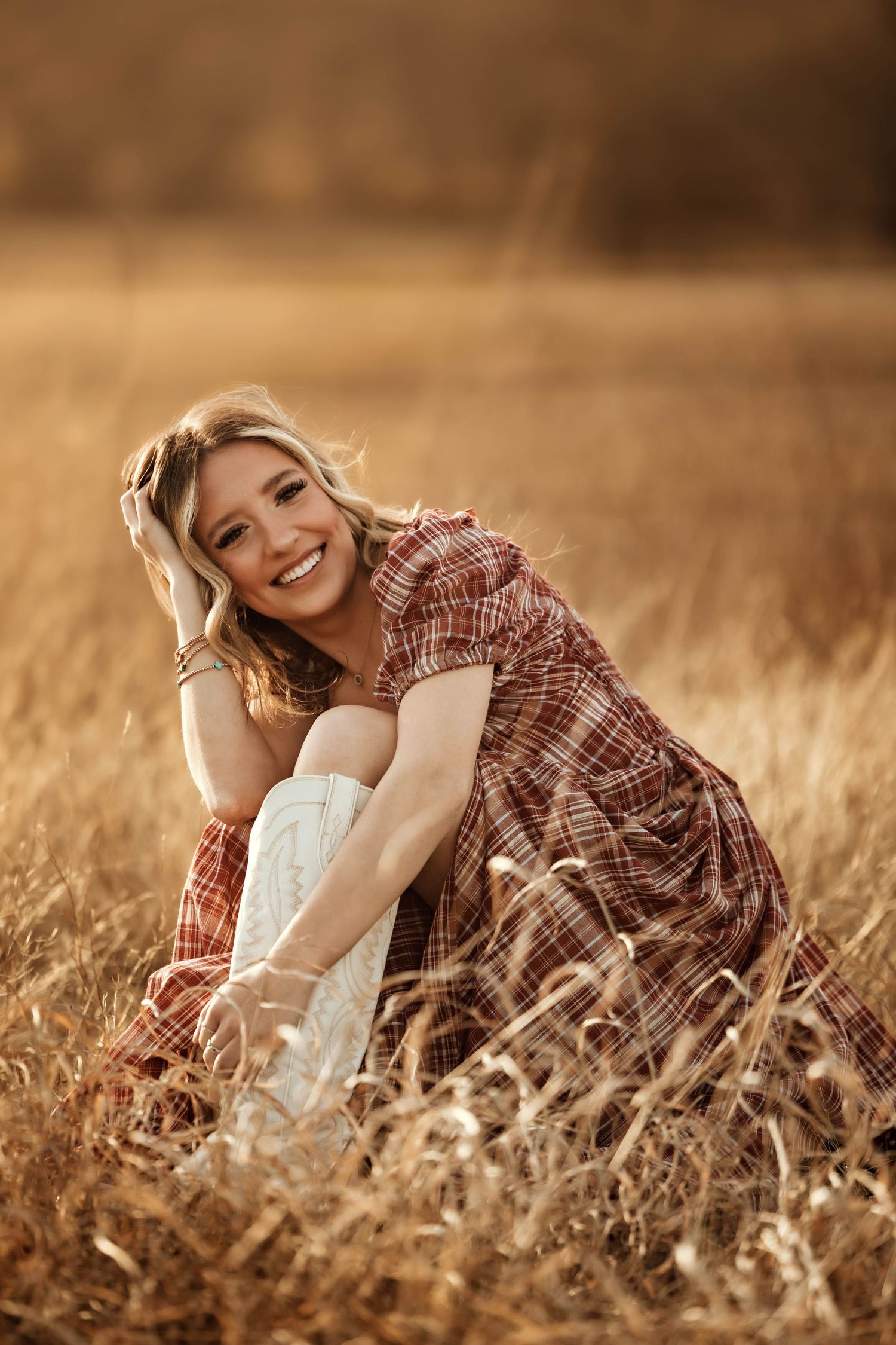 Lifestyle portrait in rustic plaid dress sitting in golden wheat field.