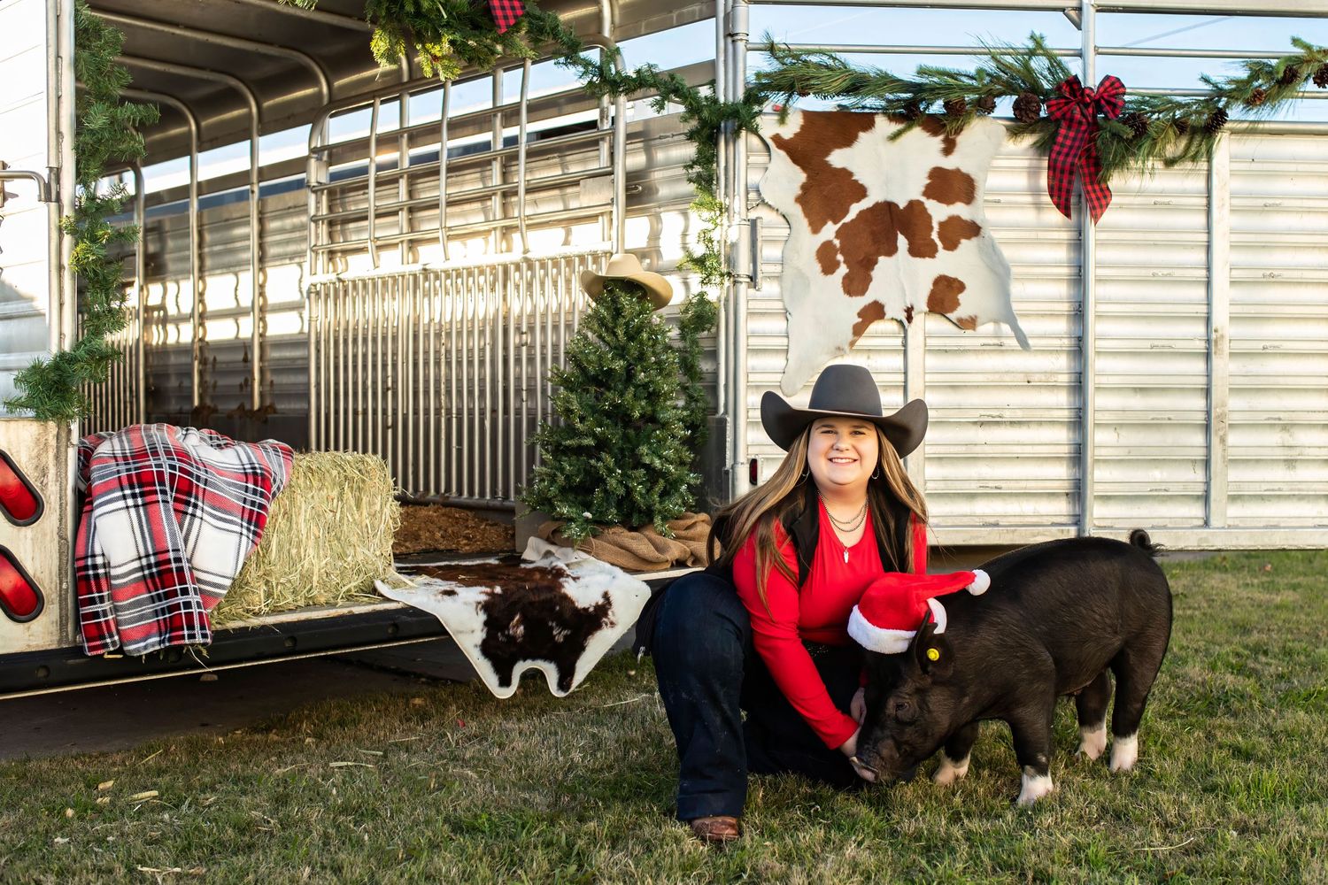 Cozy barn setting with animals and holiday decorations including hay bales and red plaid blankets.
