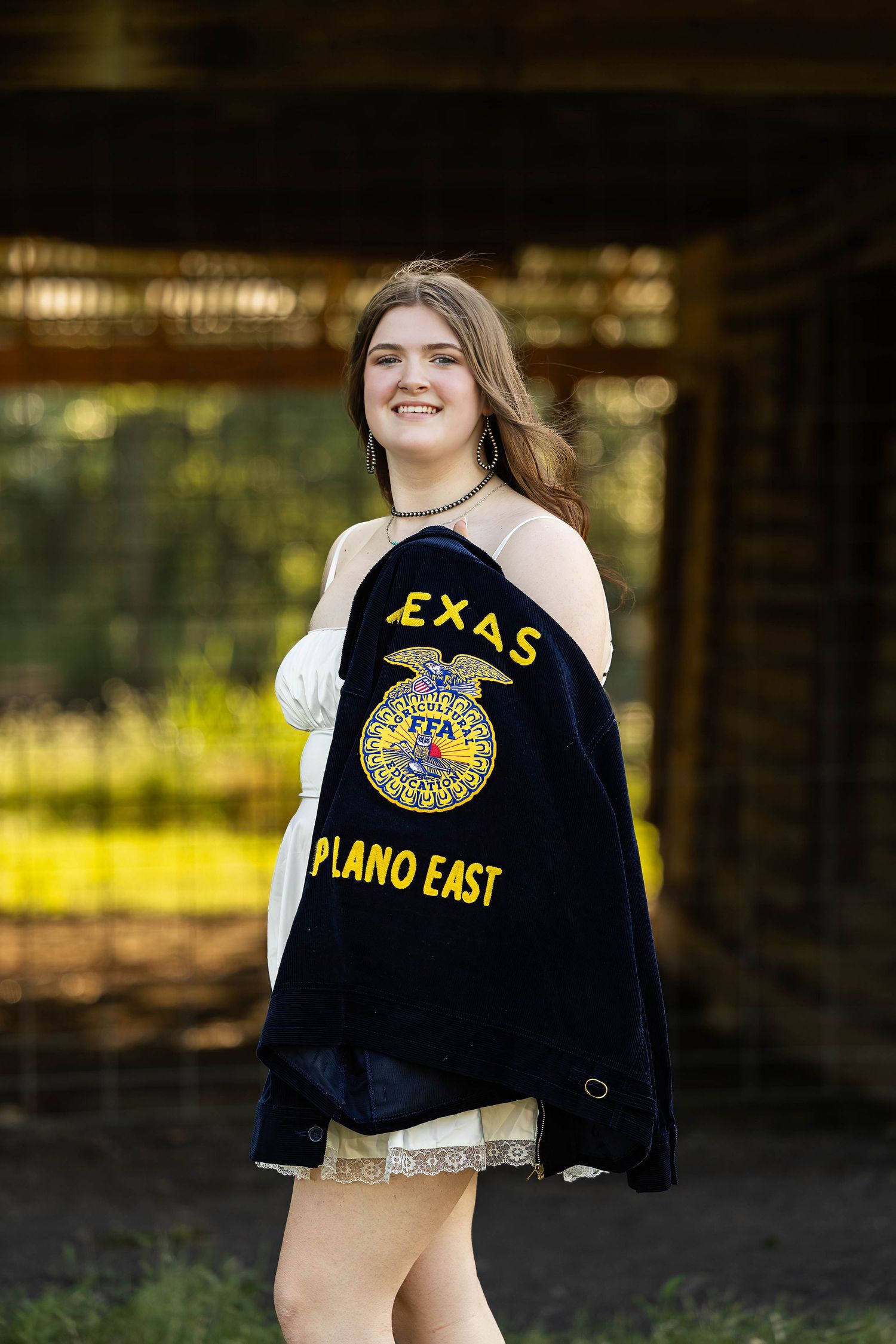 FFA member wearing Plano East chapter jacket posed in outdoor setting.