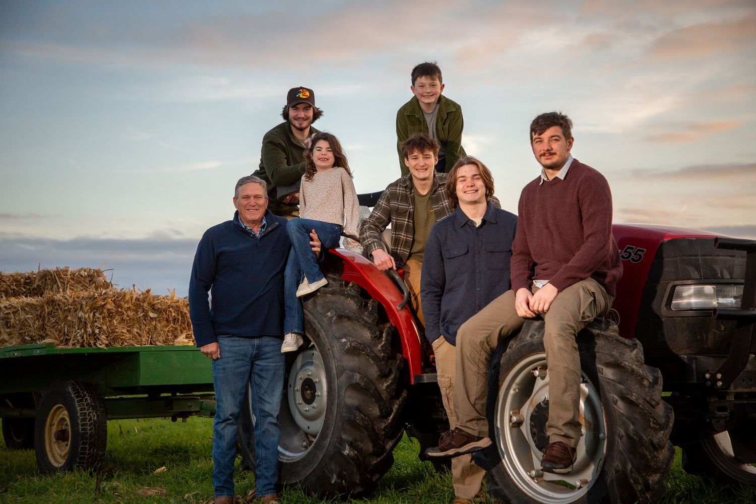 Grandfather with grandsons and granddaughter on a Case International tractor in a field with hay on the trailer Photography by Ashley Chance