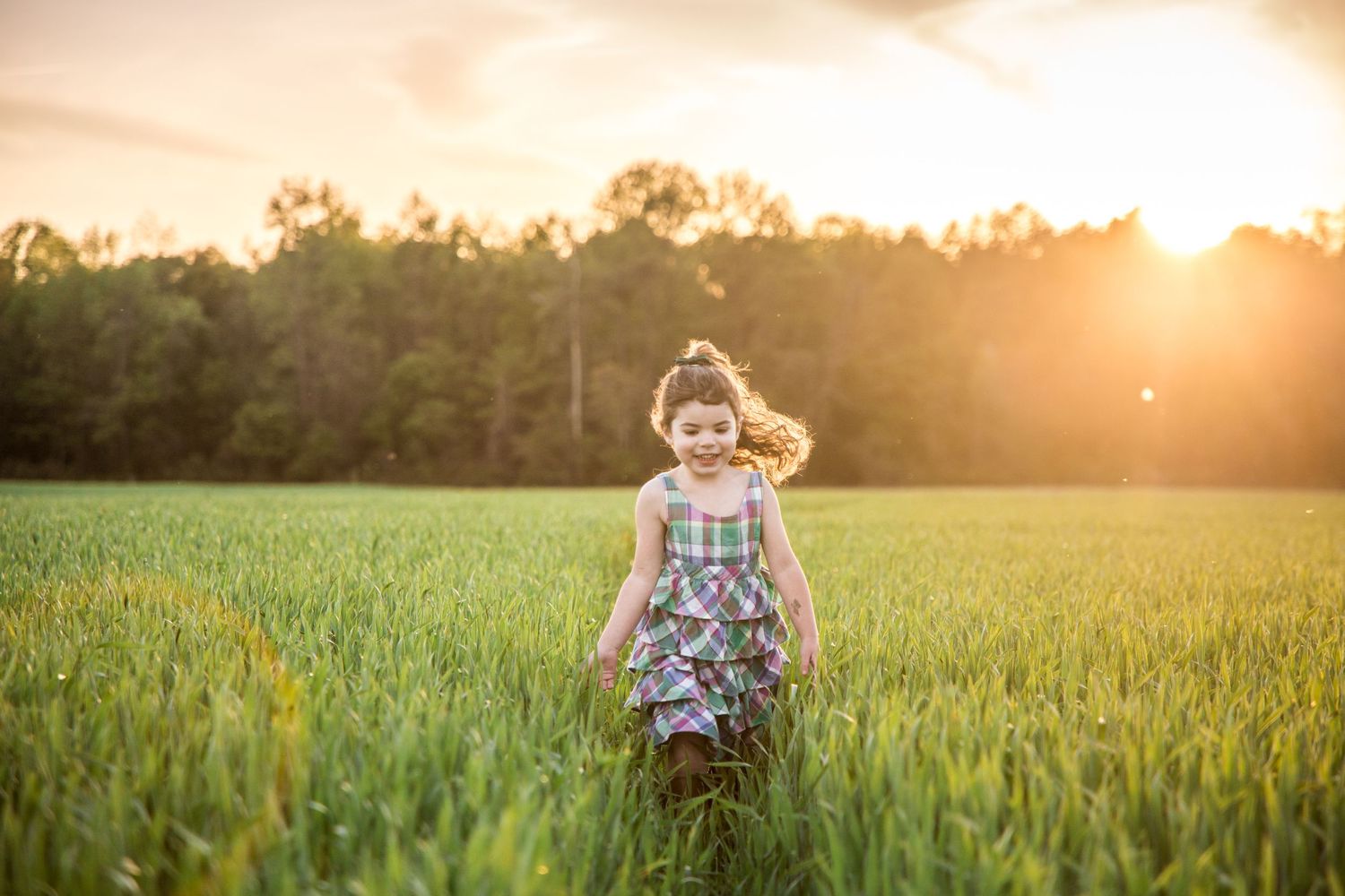 A young girl running in a field as the sun sets behind the trees photography by Ashley chance sussex county