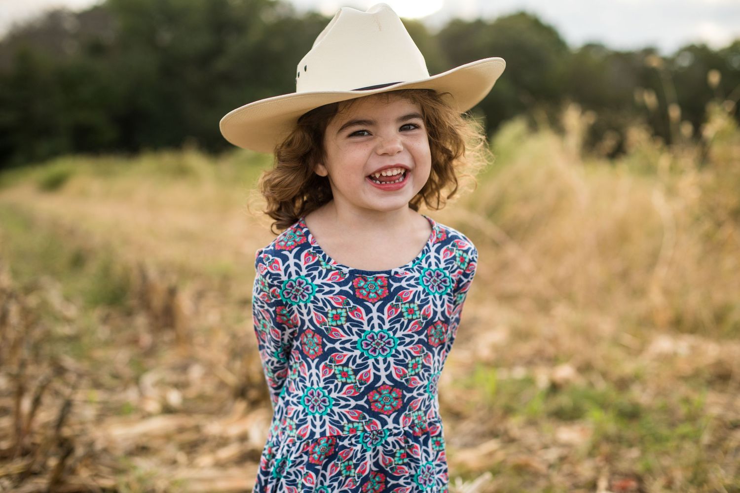 a young girl in a field of corn stalks wearing a justin cowboy hat smiling delaware farm photography